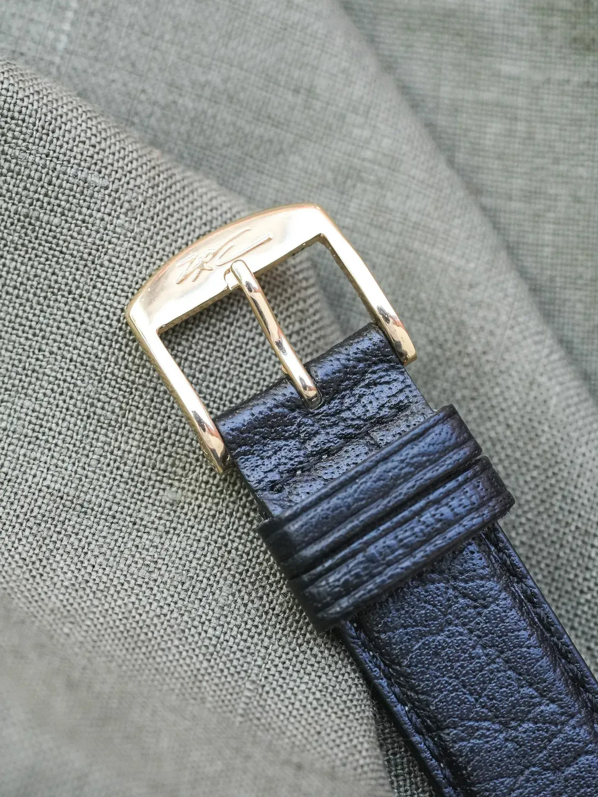 Rolex vintage watch strap with gold buckle and textured black leather on fabric