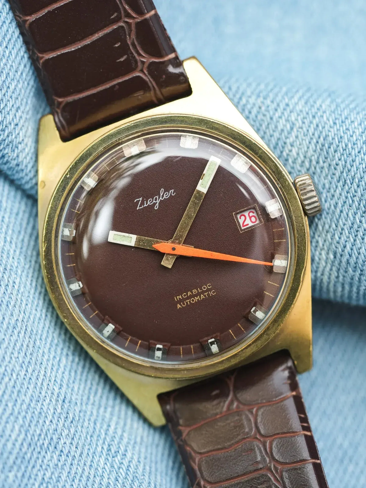 Ziegler vintage watch with brown dial, gold case, and brown crocodile strap on denim