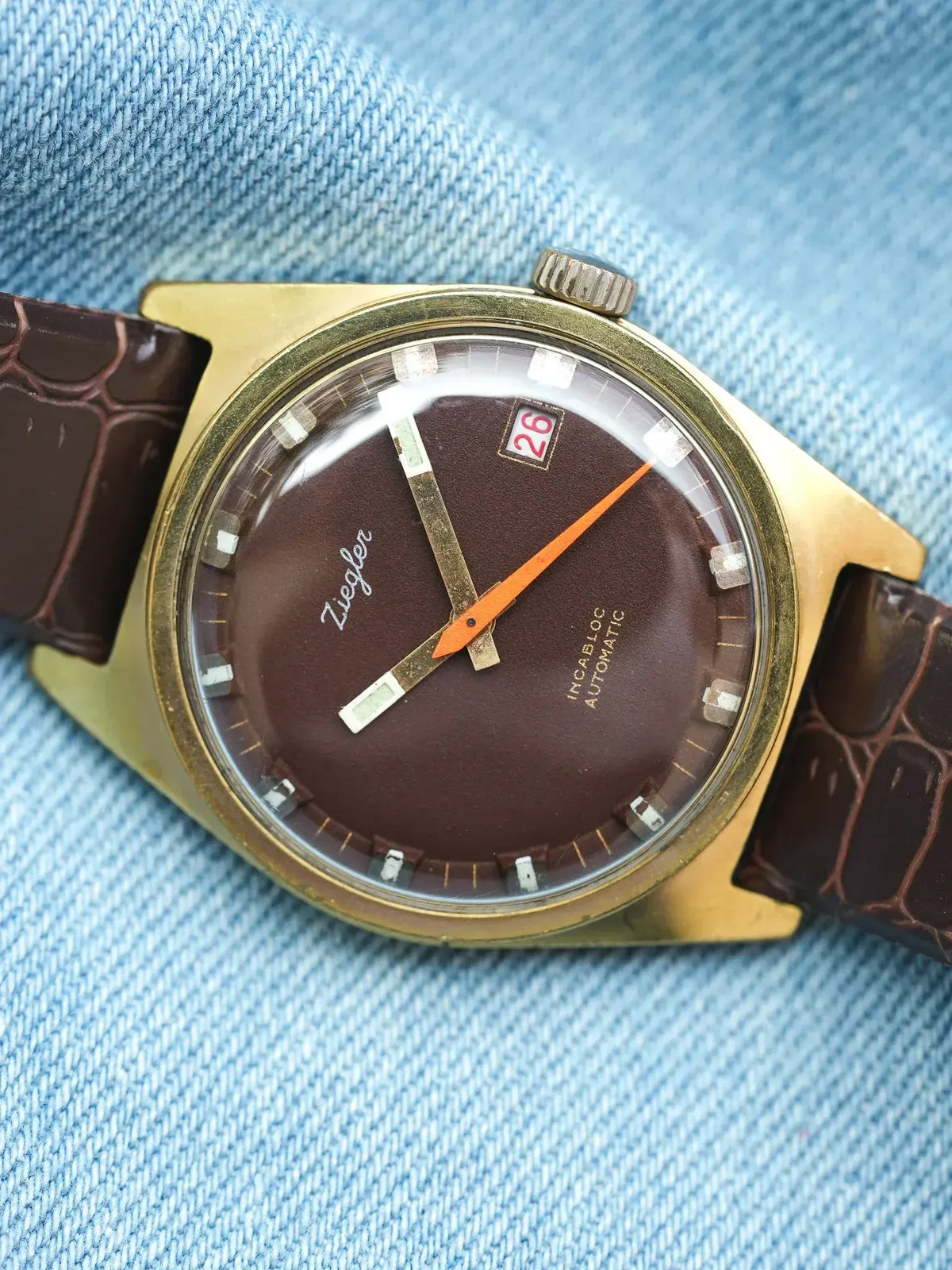Ziegler vintage watch with brown dial, gold case, and brown leather strap on denim