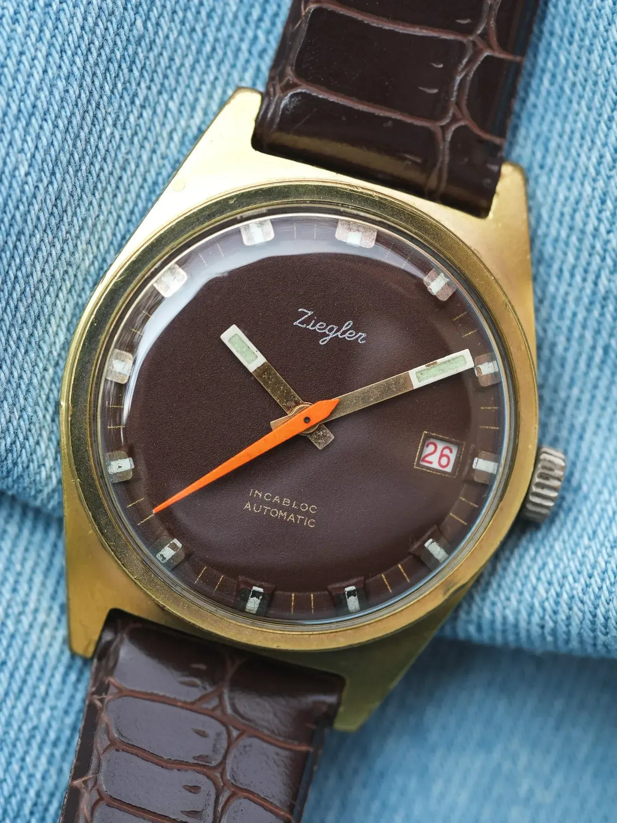 Ziegler vintage watch with brown dial, gold case, and brown alligator strap on denim