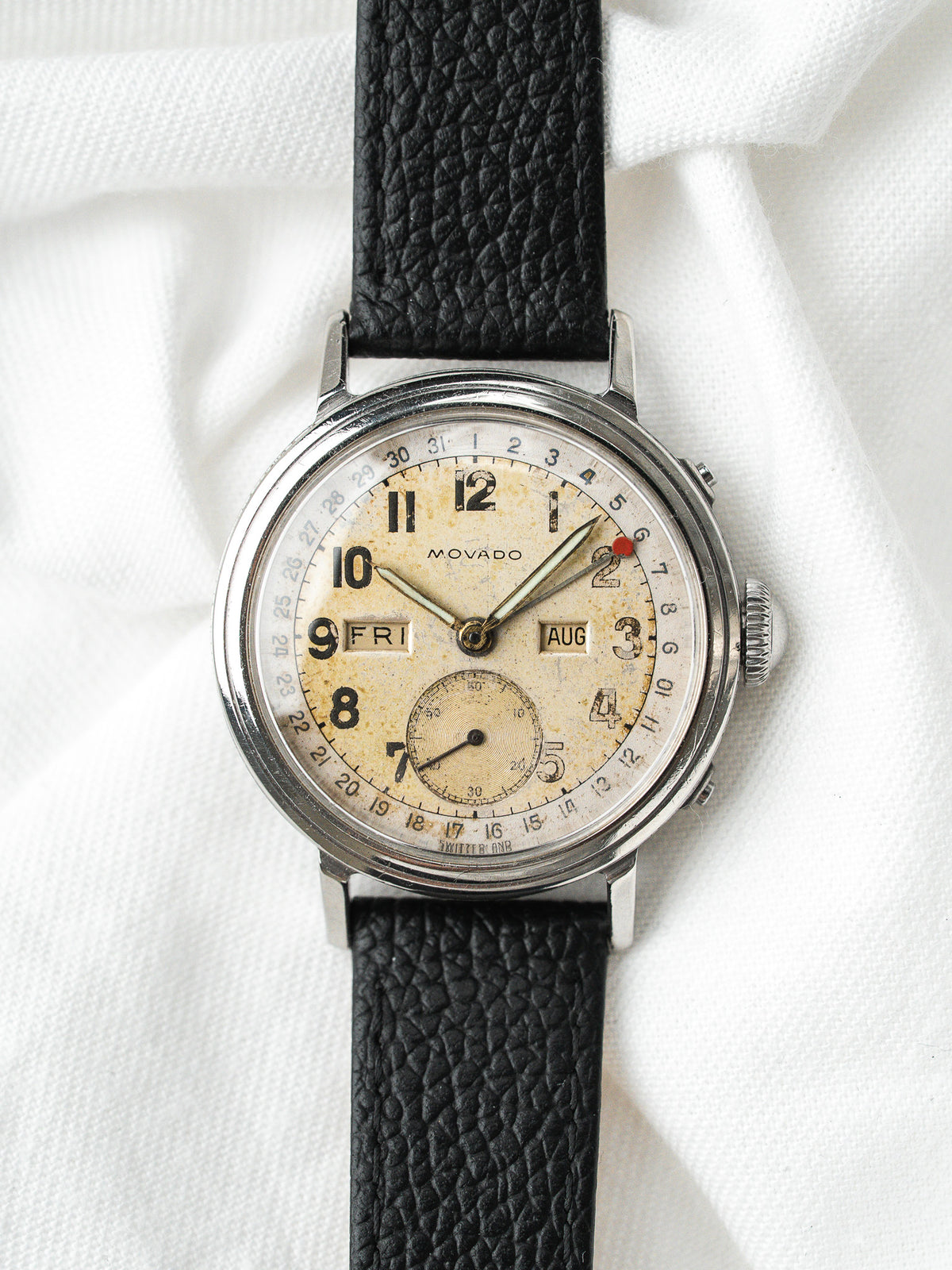 Montre Movado vintage avec cadran patiné, boîtier acier et bracelet en cuir noir