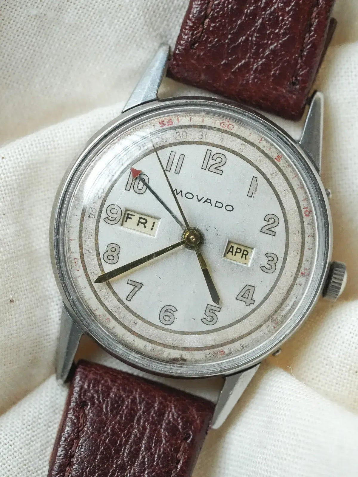 Vintage Movado watch with white dial, day-date windows, and brown leather strap