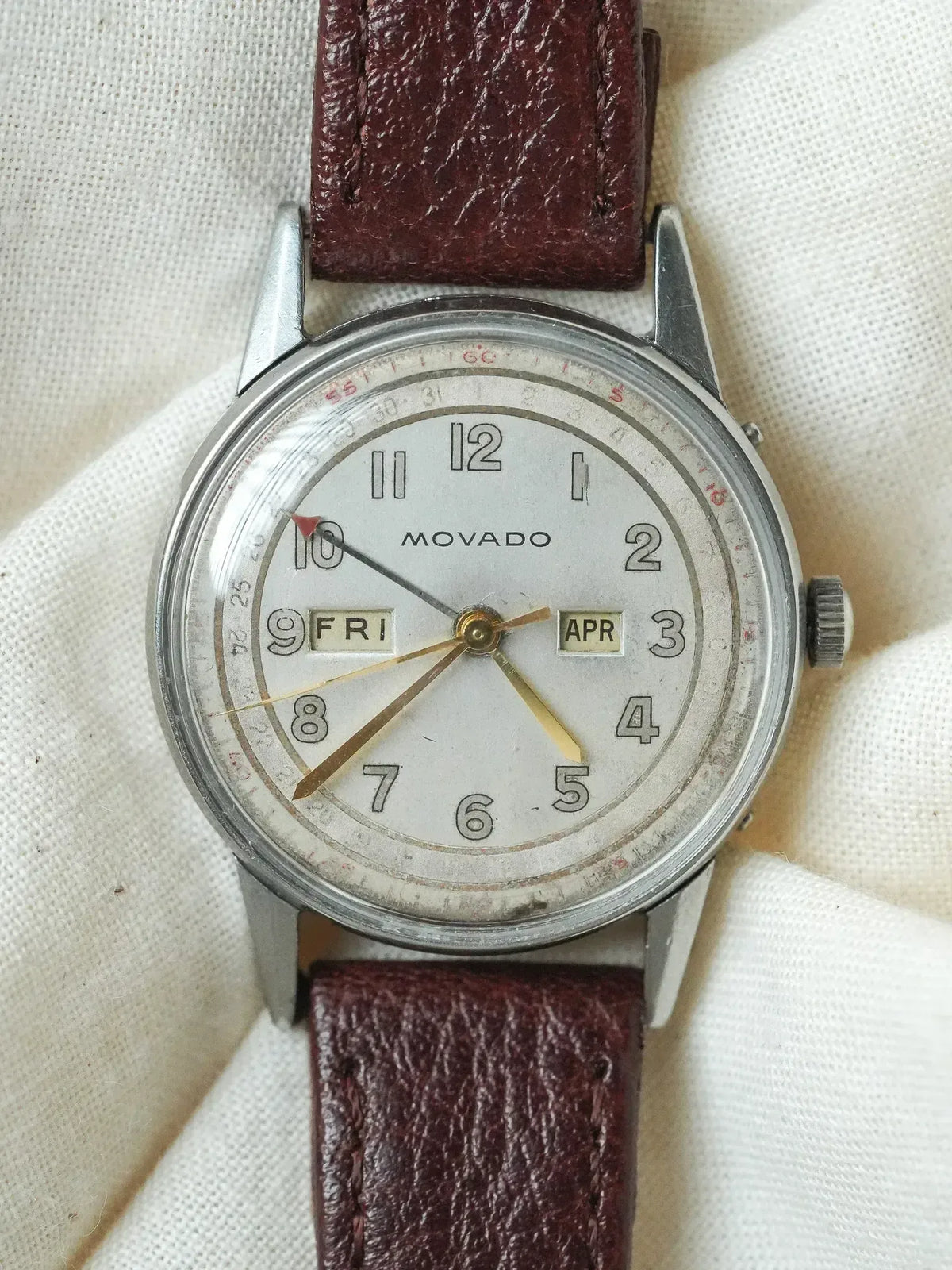 Vintage Movado watch with white dial, brown leather strap, day-date display