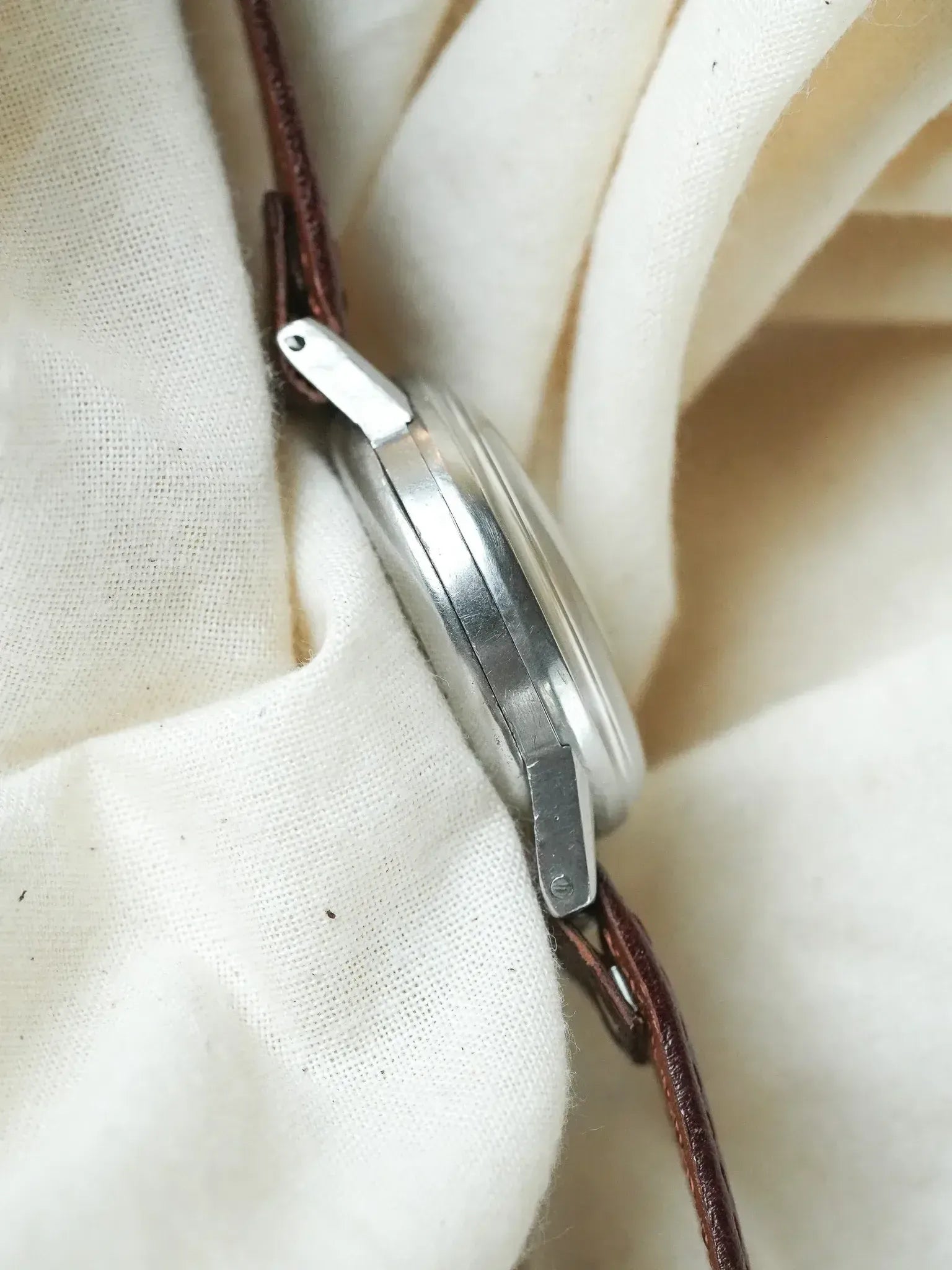 Vintage Omega watch with stainless steel case and brown leather strap on fabric