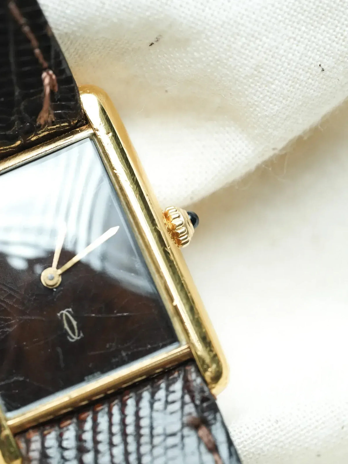 Cartier Tank vintage watch with gold case, black dial, and textured leather strap