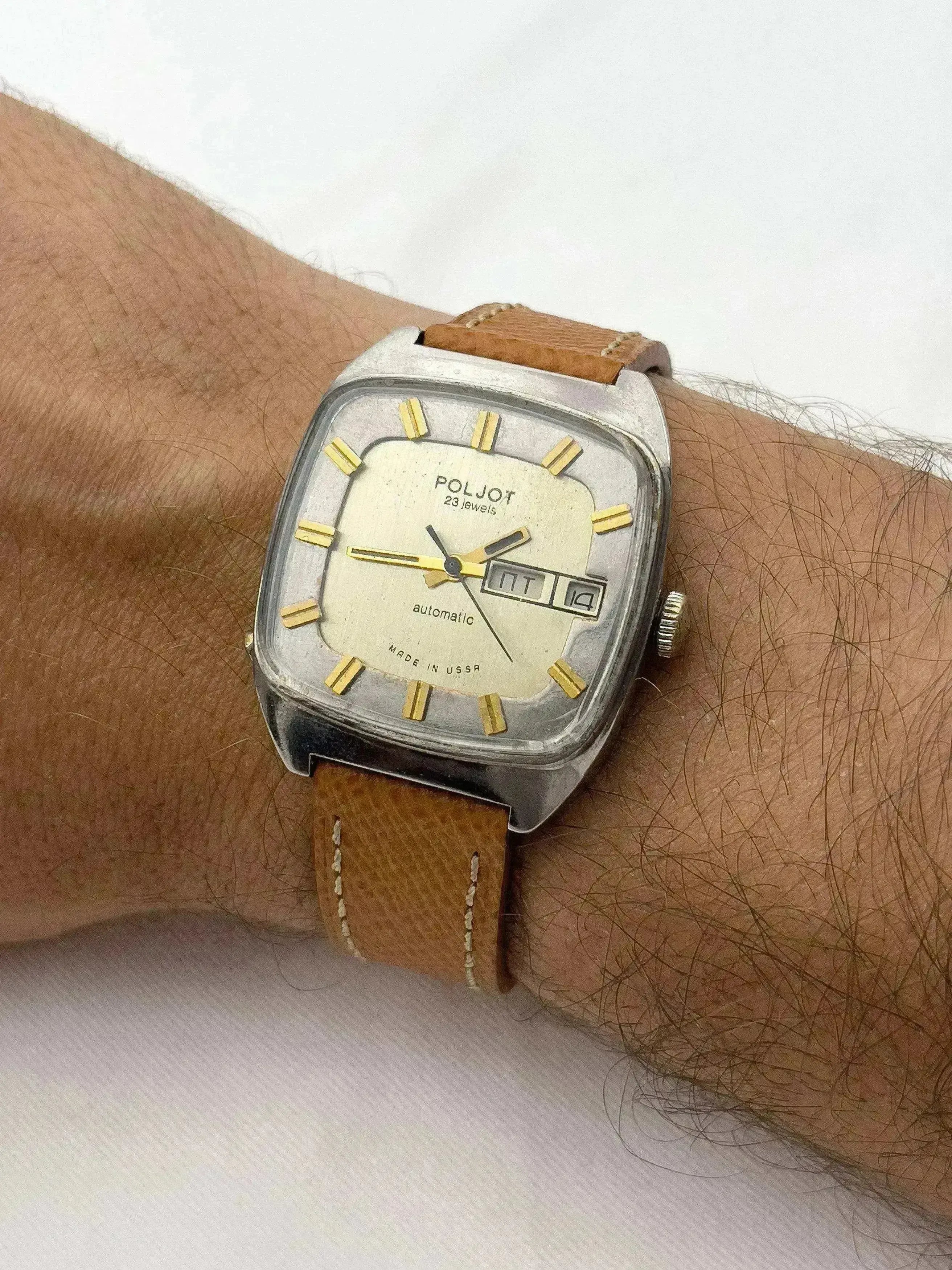 Poljot vintage automatic watch with square case, cream dial, gold markers, brown leather strap worn on wrist