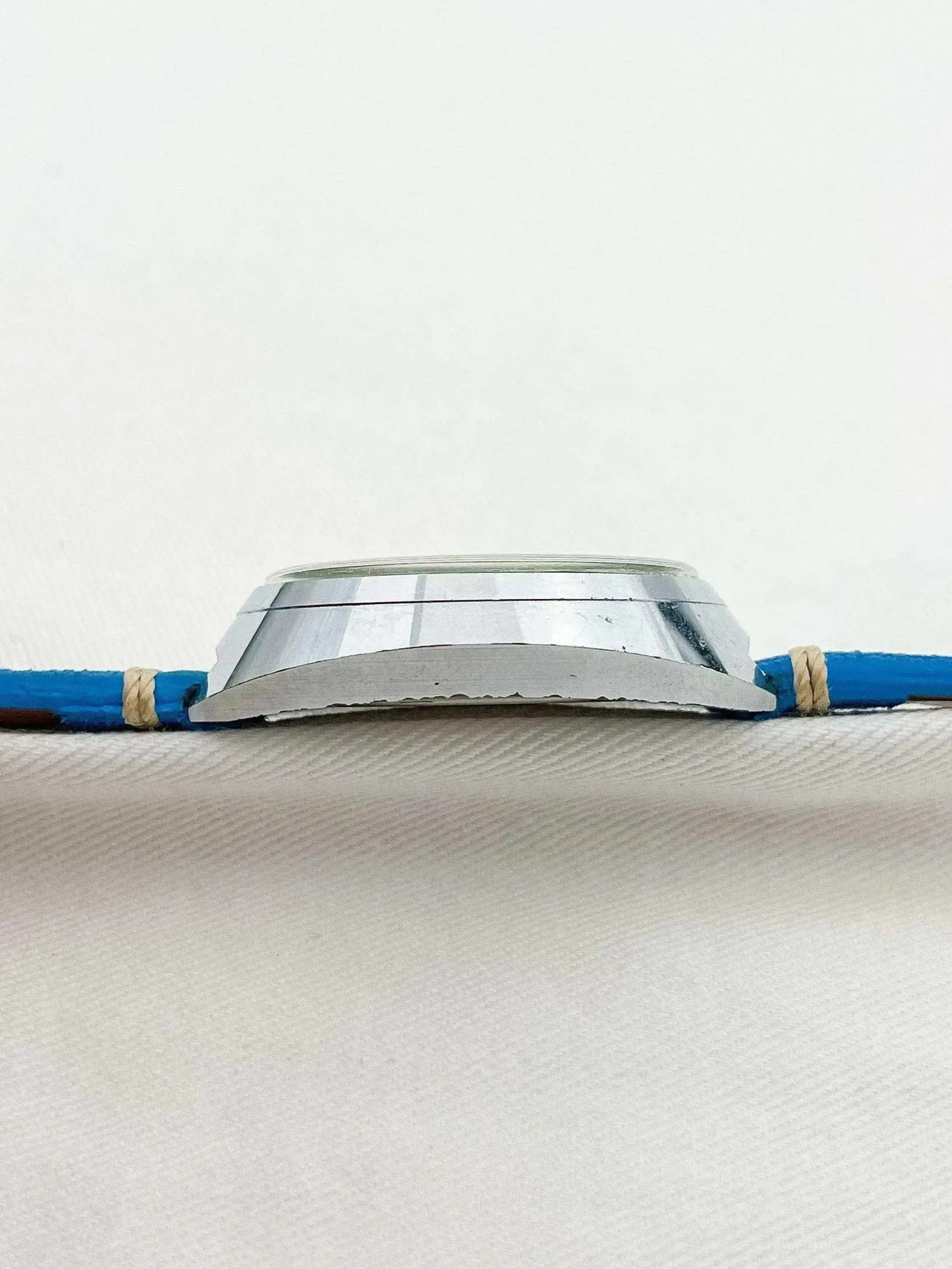 Vintage watch with blue strap and silver case on white background