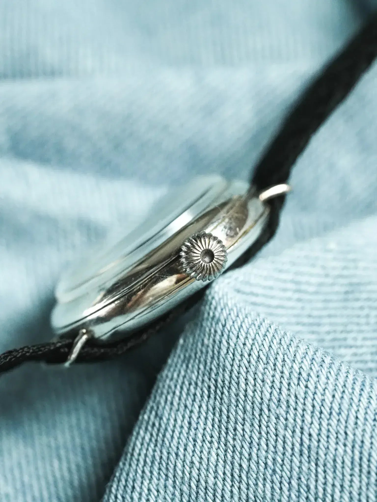 Vintage watch with fluted crown and black strap on denim