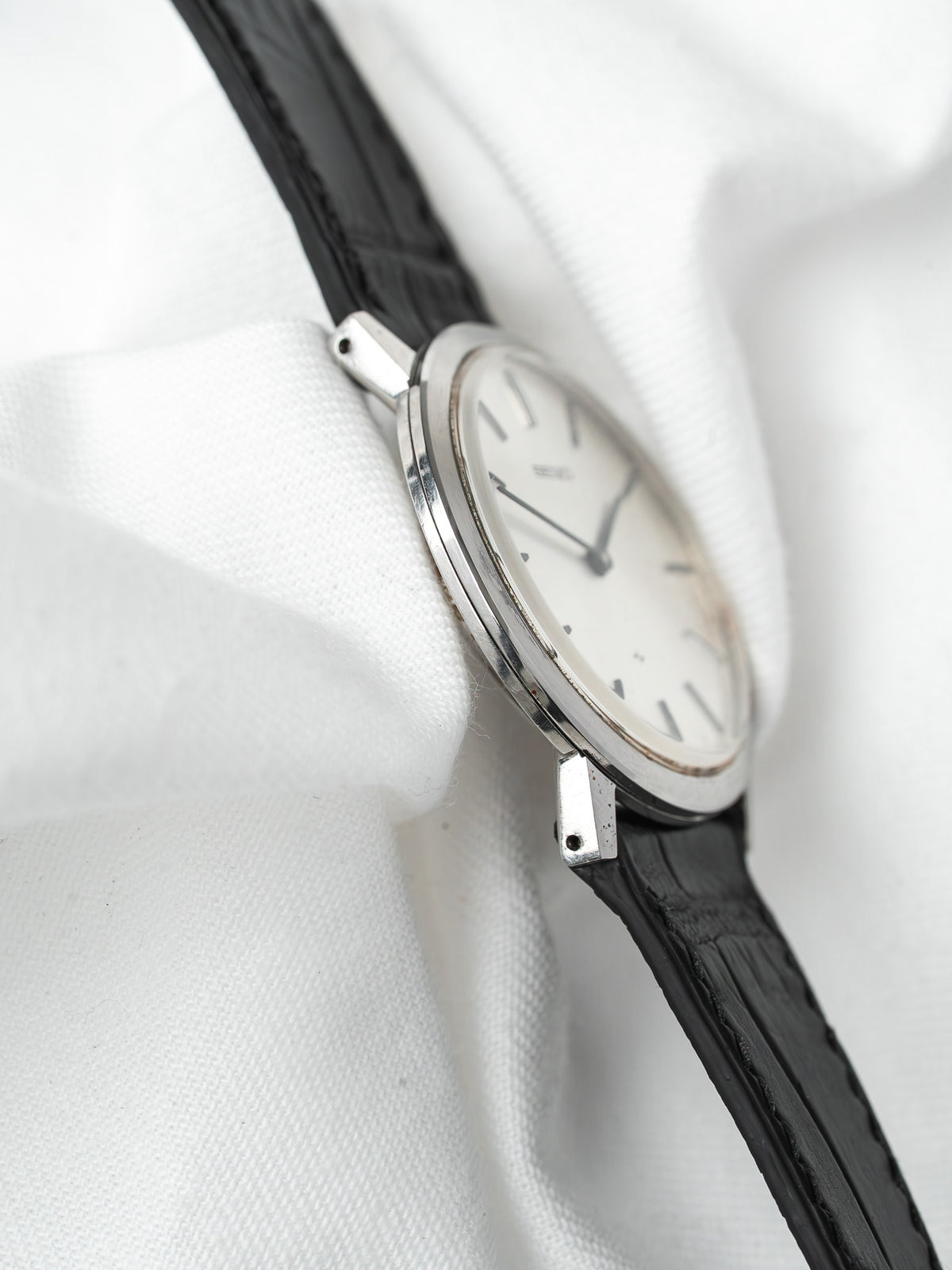 Vintage Seiko watch with white dial, black leather strap, and silver case