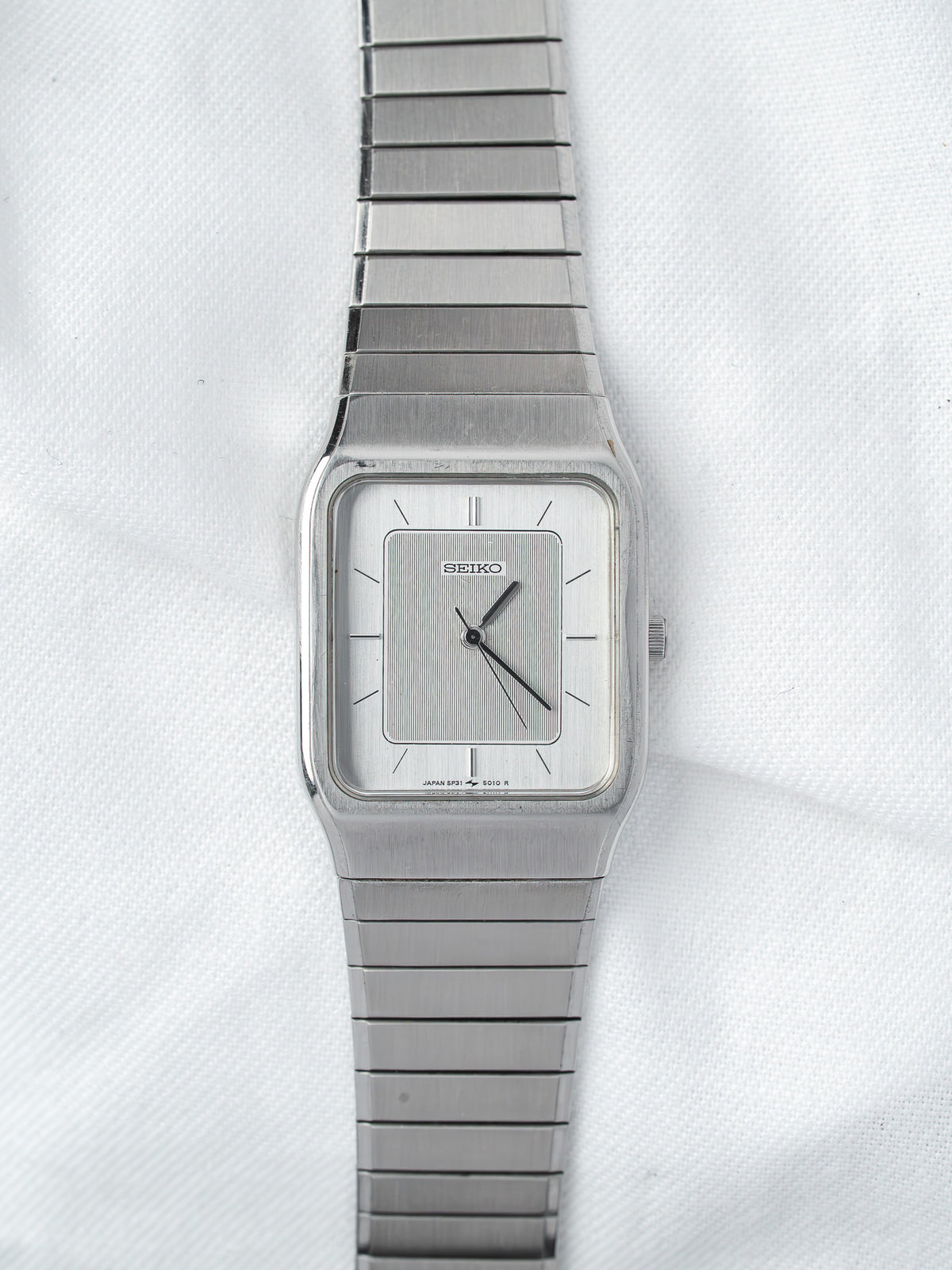 Seiko vintage watch with square case, silver dial, and metal bracelet on white background
