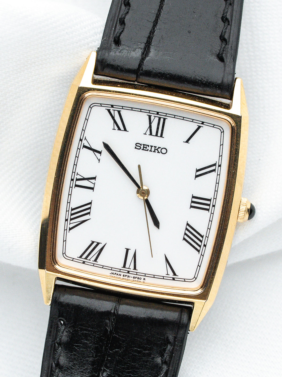 Seiko vintage watch with gold case, white dial, Roman numerals, black leather strap