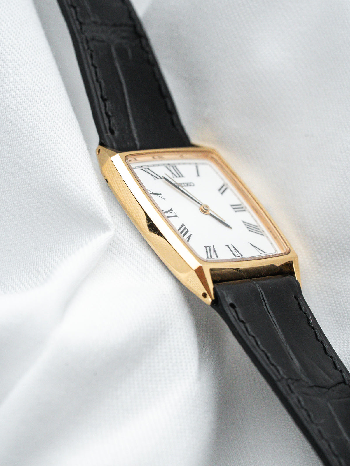 Cartier vintage watch with gold case, white dial, Roman numerals, black leather strap
