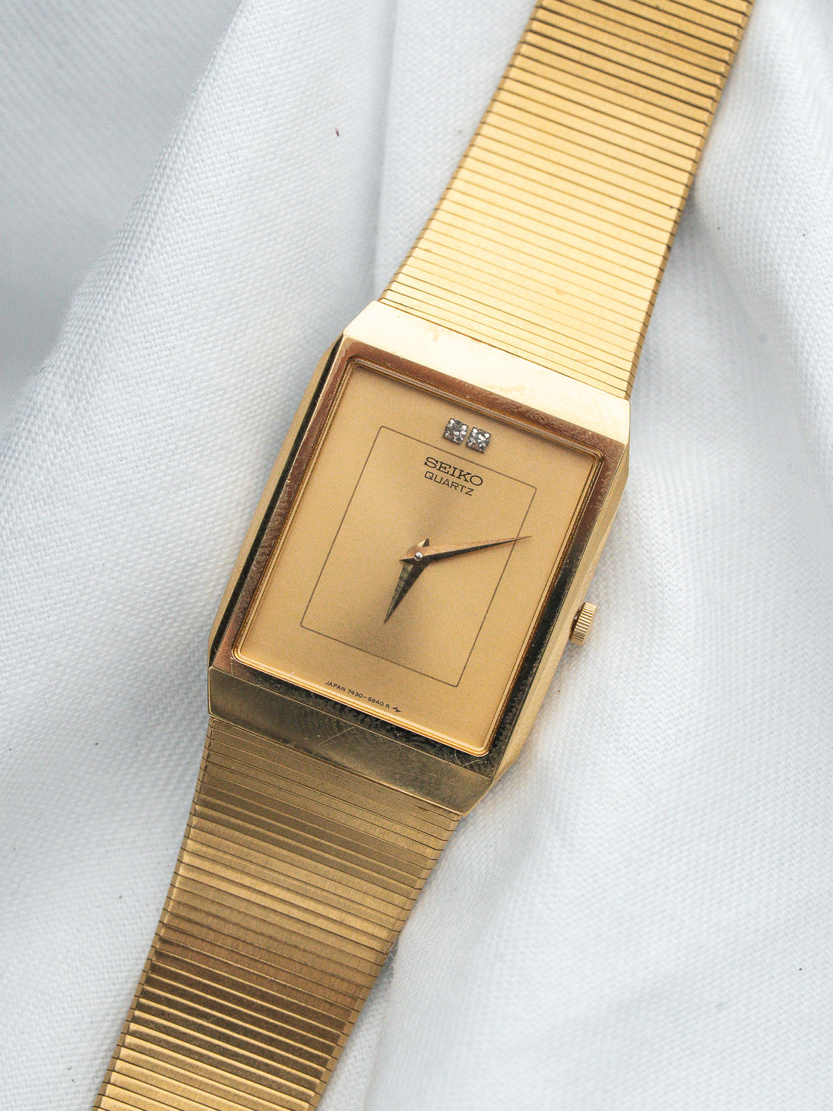 Seiko Quartz vintage watch with gold-tone case and bracelet, beige dial on white fabric