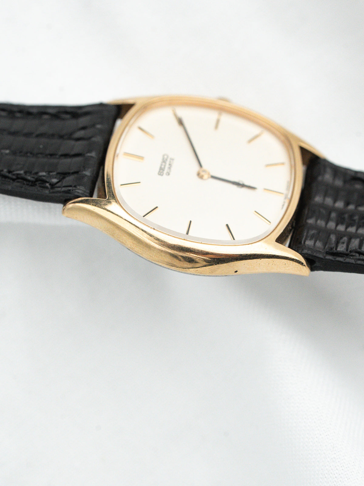 Seiko vintage watch with gold case, white dial, black textured strap