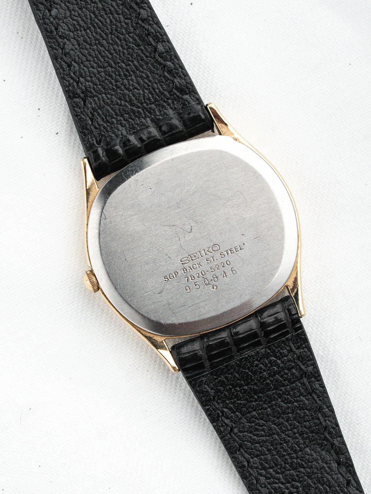 Seiko vintage watch with gold-tone case, black leather strap, stainless steel back engraved