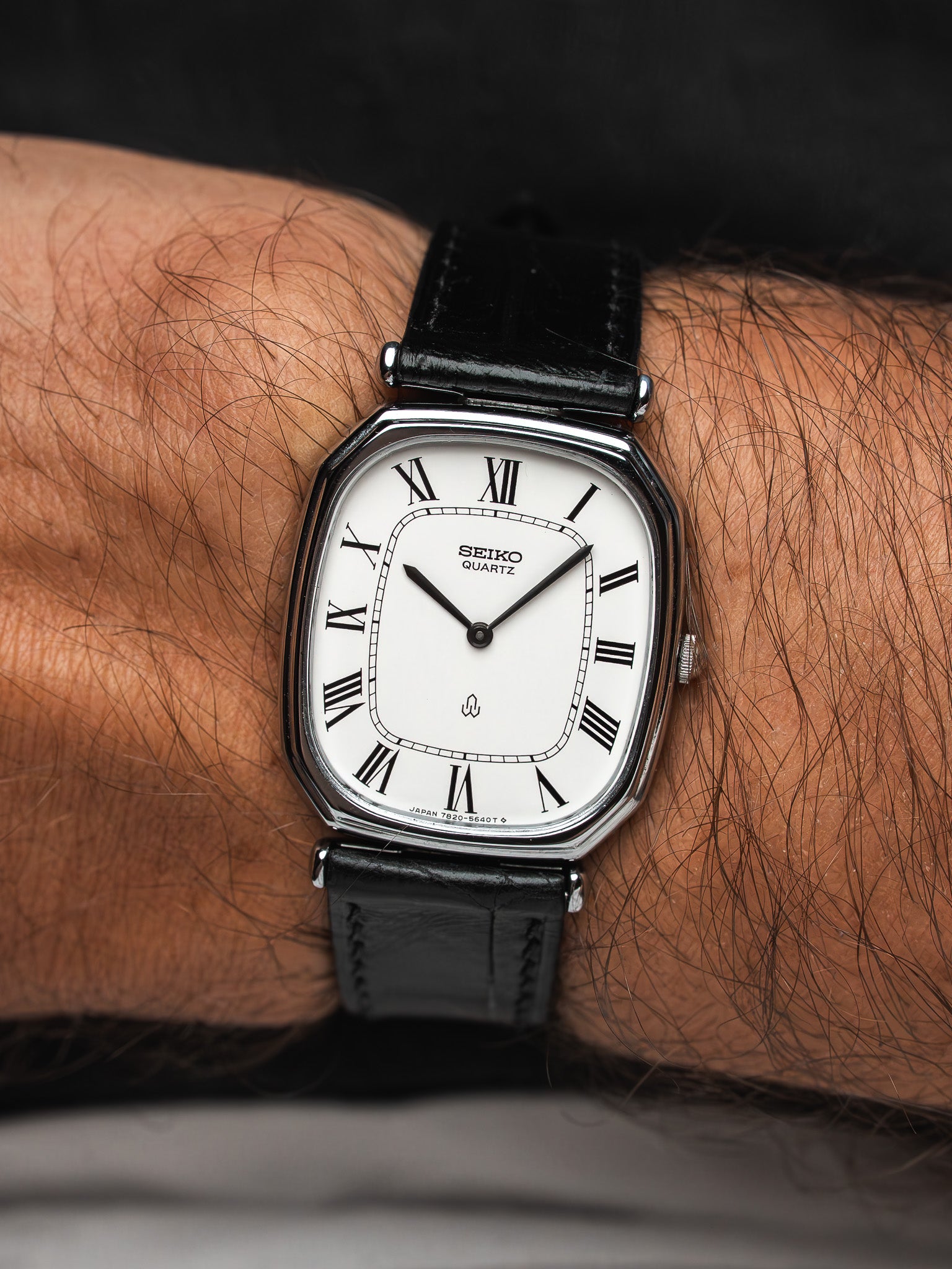 Seiko Quartz vintage watch with white dial Roman numerals black leather strap on wrist
