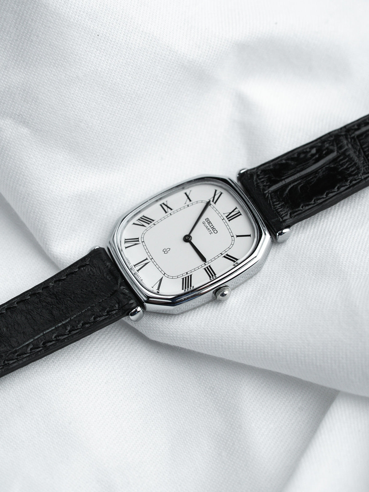 Seiko quartz watch with white dial, Roman numerals, black leather strap