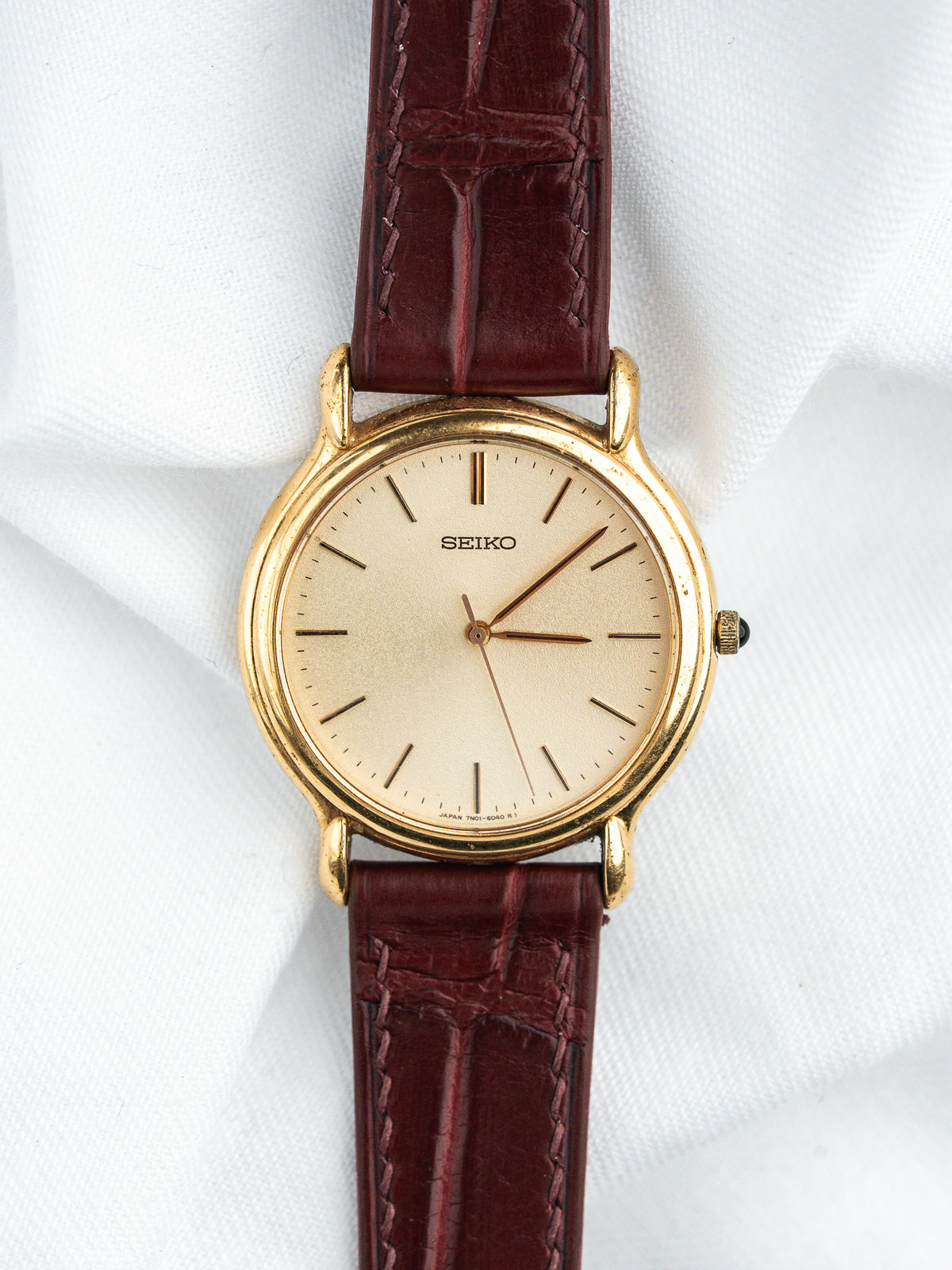 Seiko vintage watch with gold case, cream dial, and burgundy leather strap