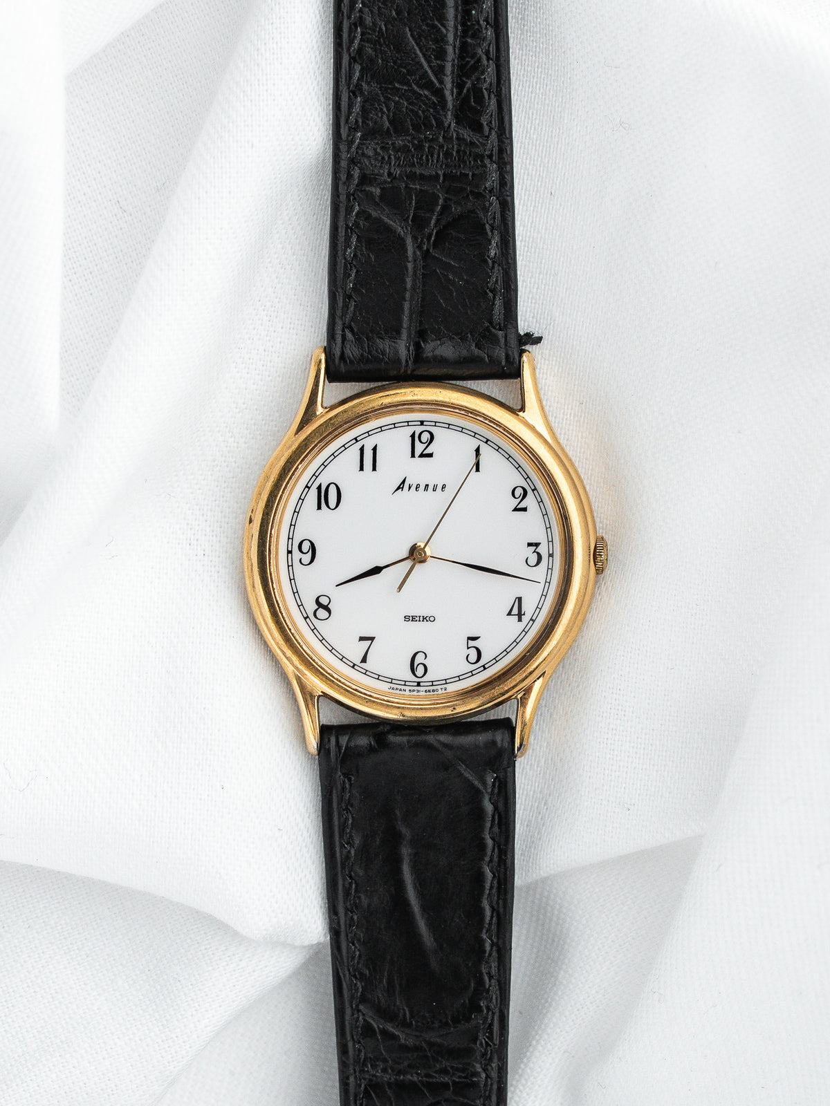 Montre Seiko Avenue vintage, boîtier rond doré, cadran blanc et bracelet cuir noir