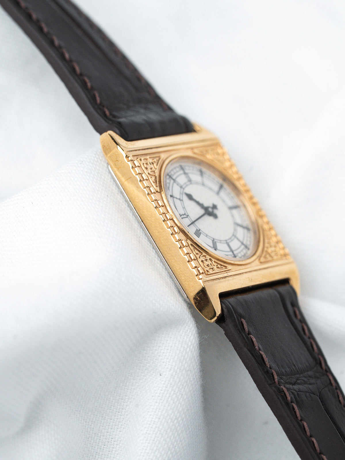Vintage Cartier Tank watch with gold case, white dial, and black leather strap