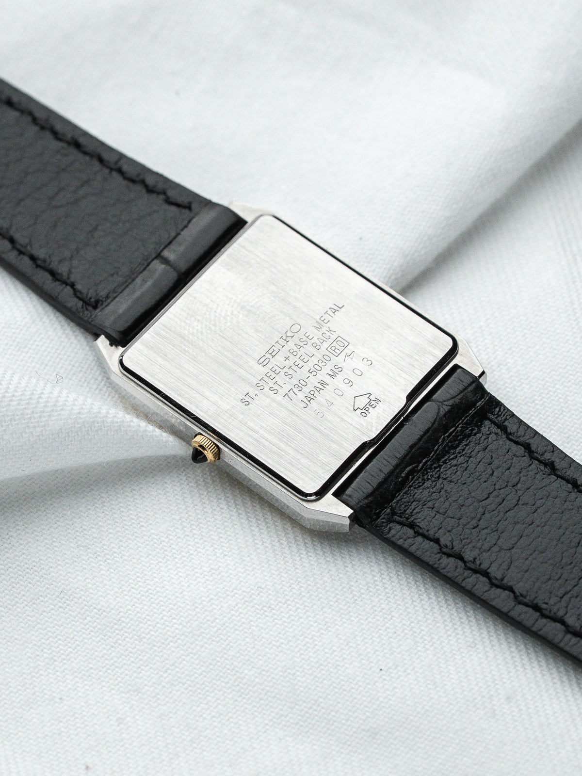Seiko vintage watch with steel case, black leather strap, and engraved back details