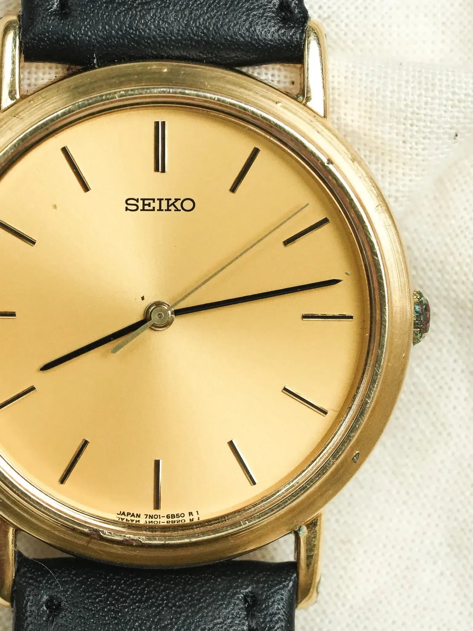 Seiko vintage watch with gold dial, black leather strap, and gold case