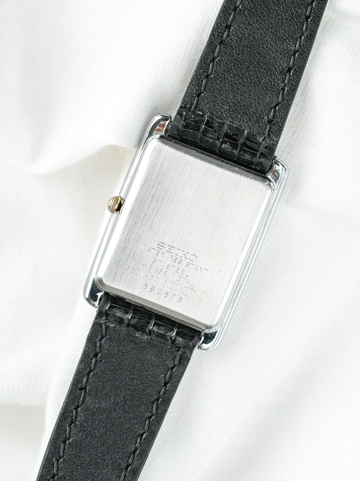 Dos d'une montre Seiko vintage, boîtier rectangulaire en acier et bracelet cuir noir