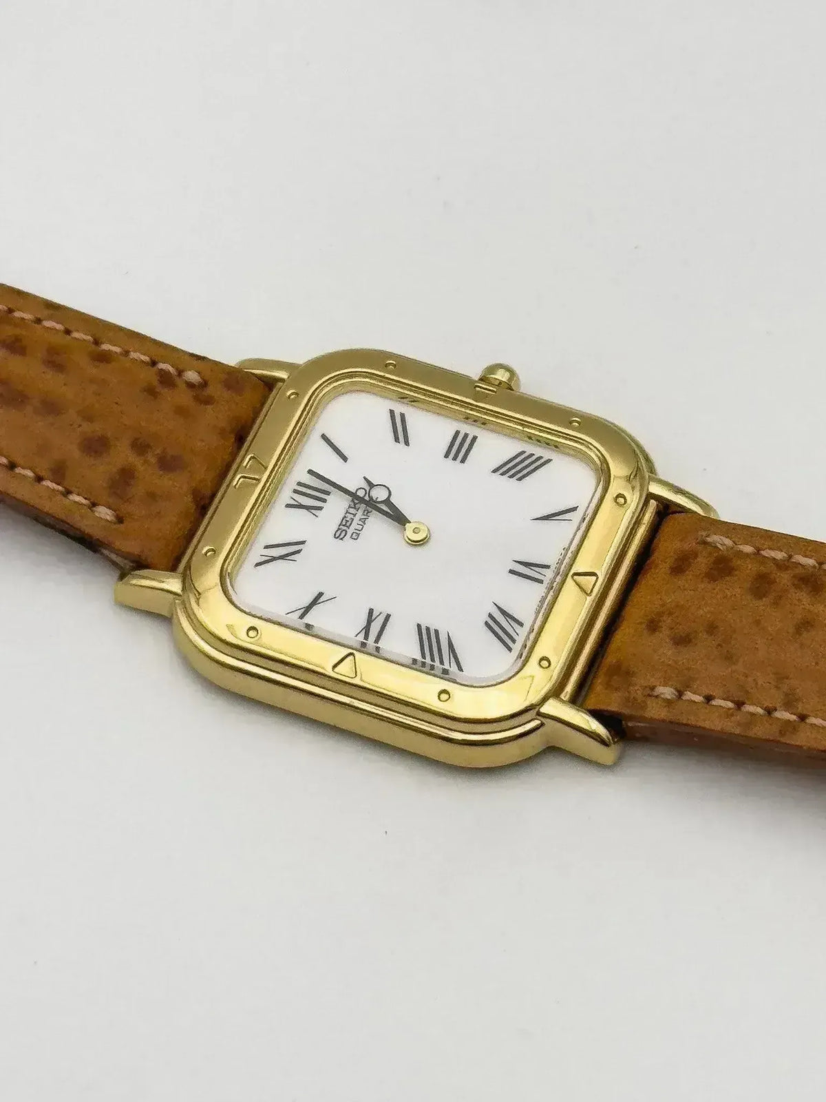 Seiko quartz watch with gold case, white dial, Roman numerals, brown leather strap