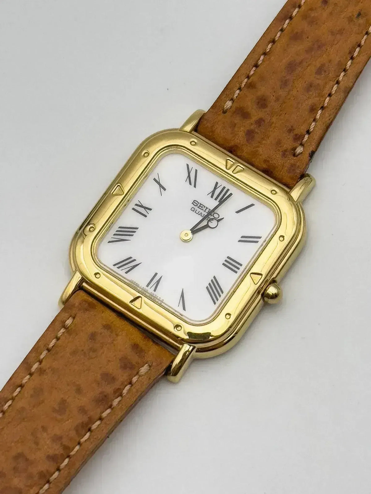 Seiko vintage watch with gold case, white dial, Roman numerals, and brown leather strap