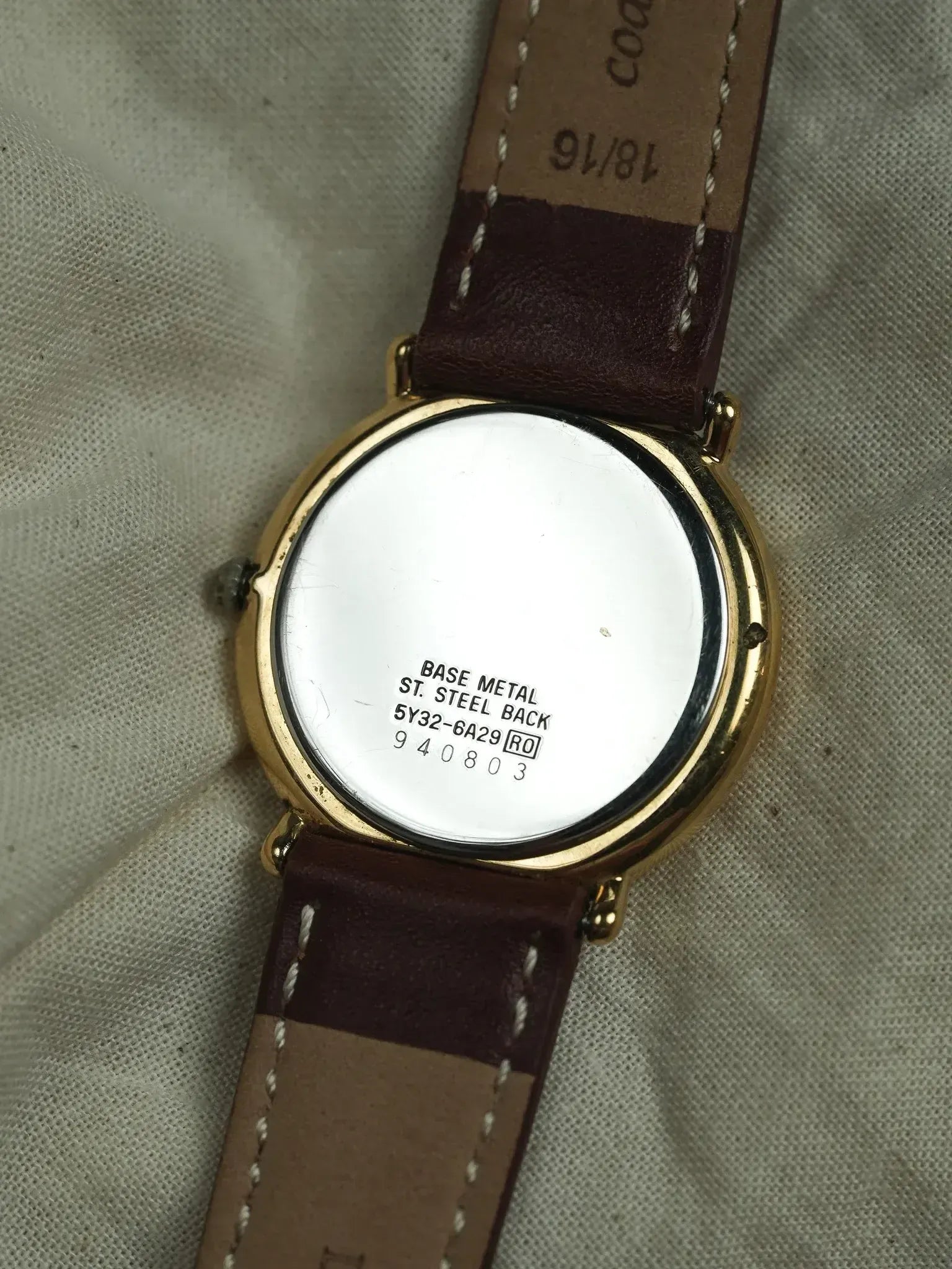 Vintage watch with gold case, brown leather strap, steel back marked BASE METAL
