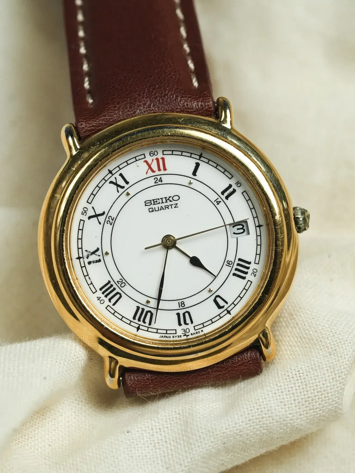 Seiko Quartz vintage watch with gold case, white dial, Roman numerals, brown leather strap