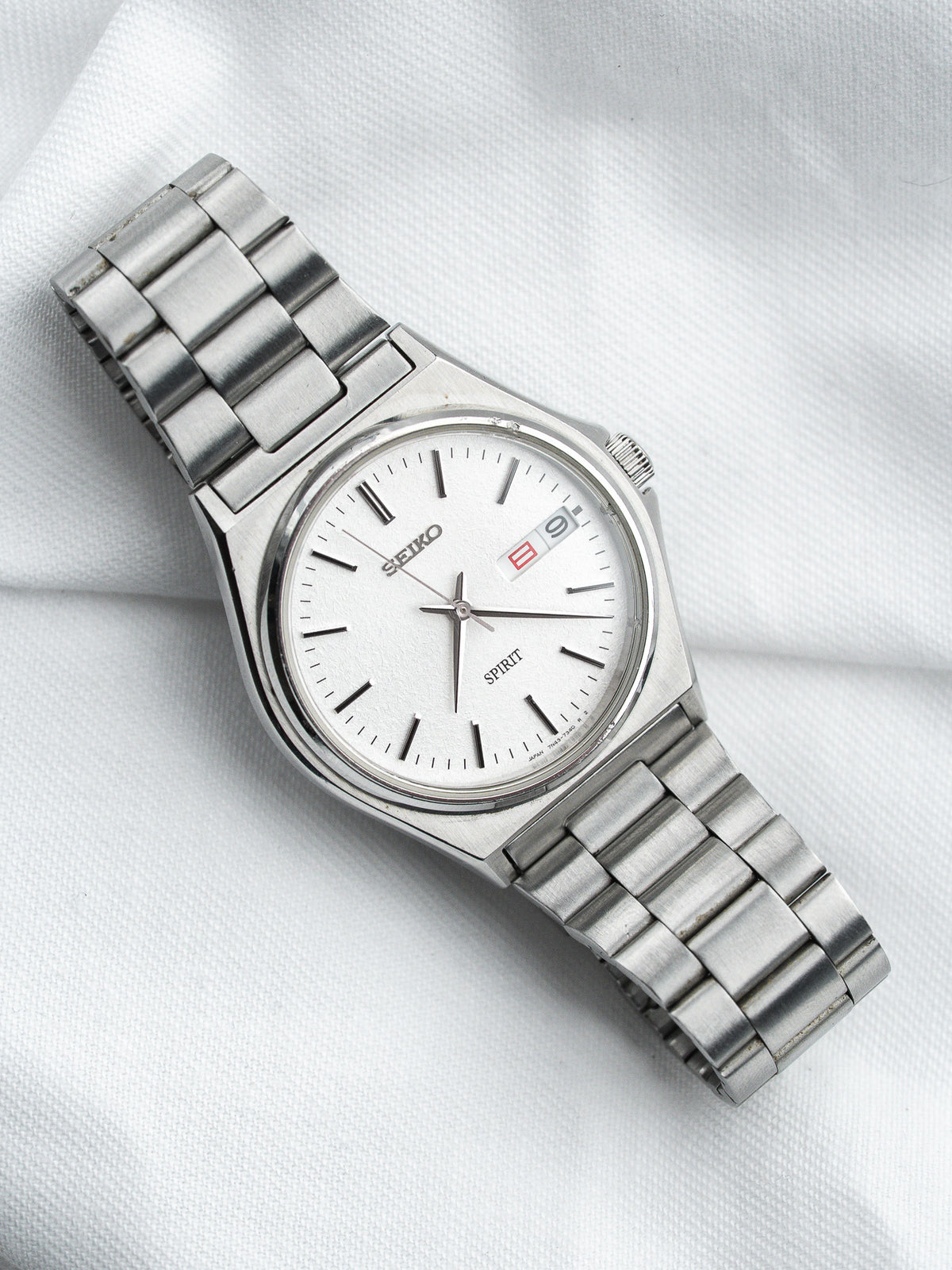 Seiko Spirit vintage watch with white dial, steel bracelet, date window on white fabric