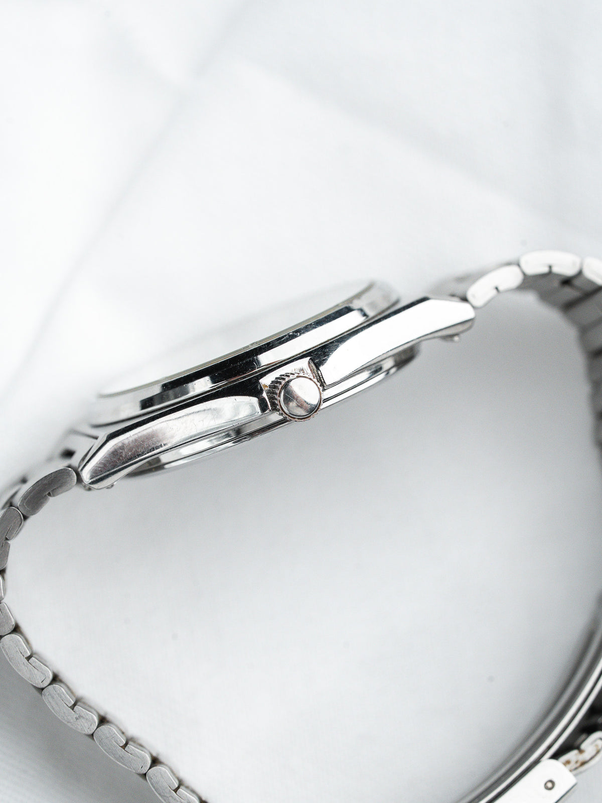 Vintage Omega watch with polished steel case and integrated bracelet on white background