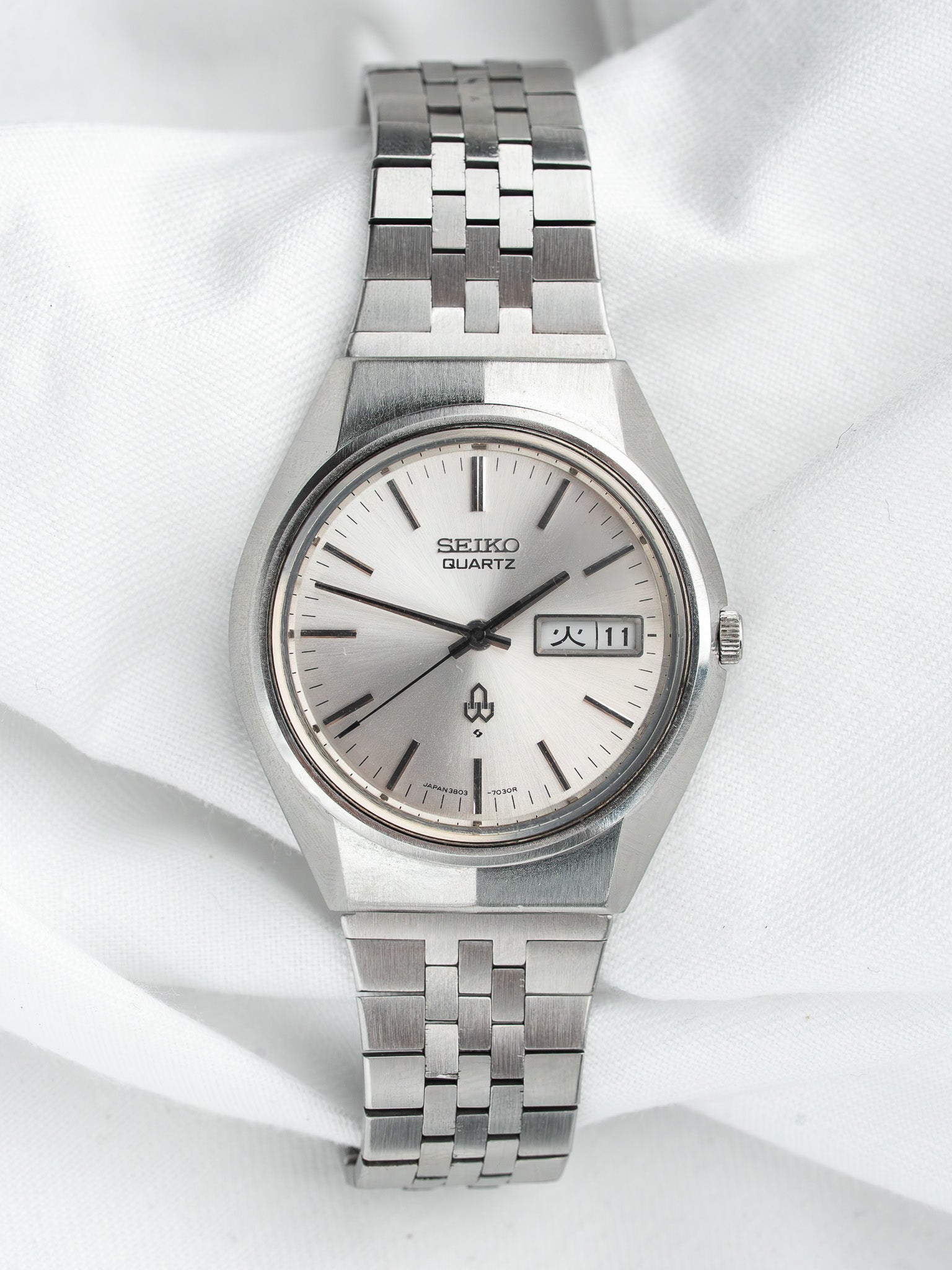 Seiko Quartz vintage watch with silver dial, day-date window, and steel bracelet on white fabric