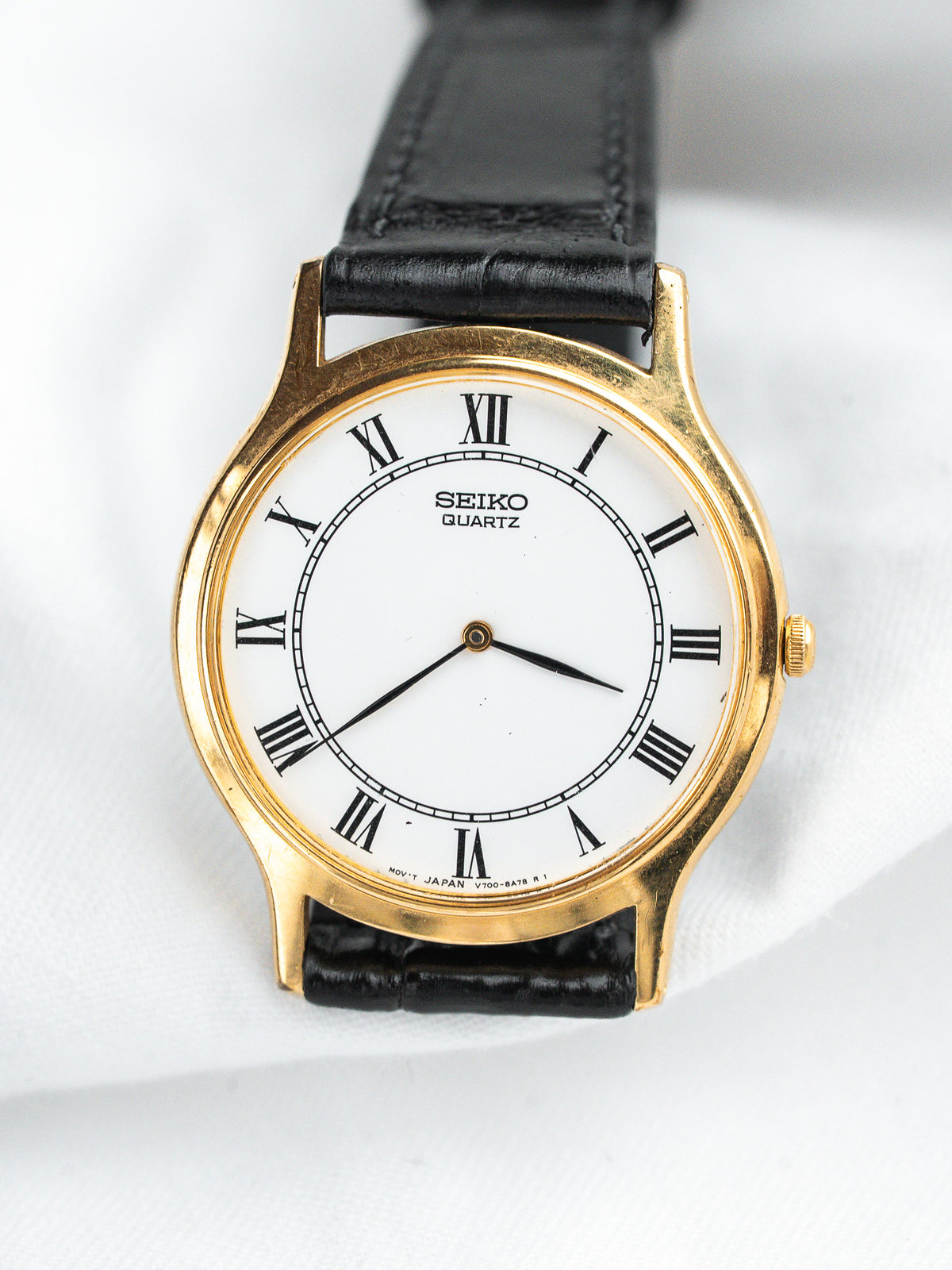 Seiko Quartz vintage watch with gold case, white dial, Roman numerals, black leather strap
