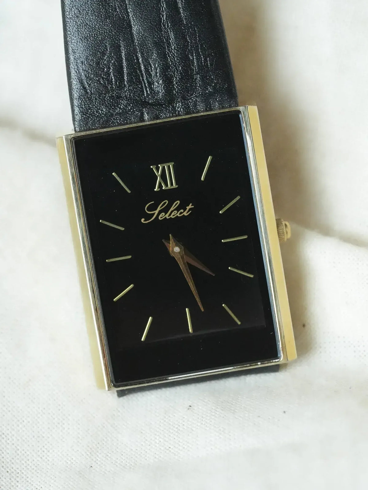 Select vintage watch with black dial, gold case, and black leather strap