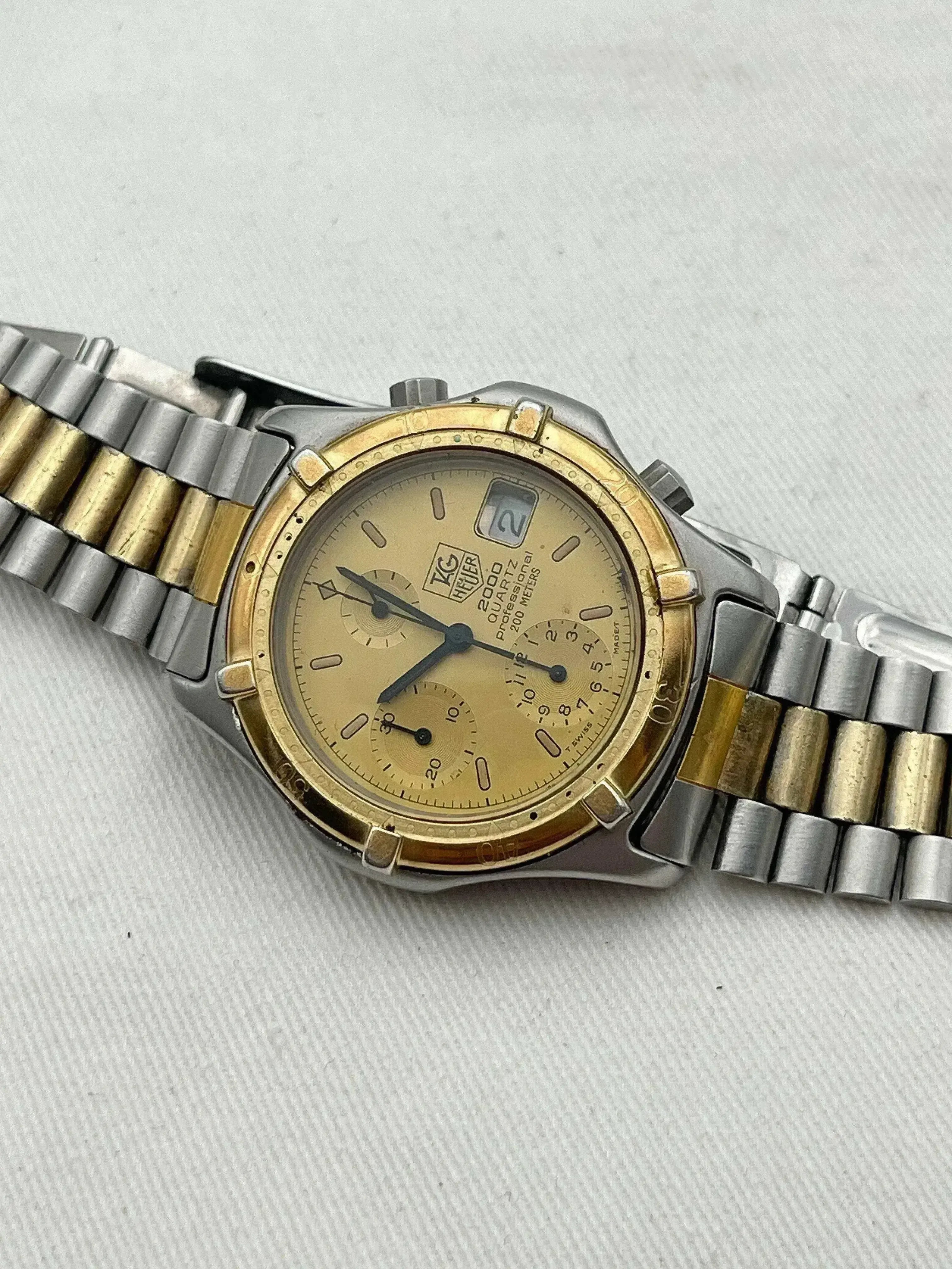 TAG Heuer 2000 Quartz Professional vintage watch with gold dial, two-tone bracelet, on neutral background