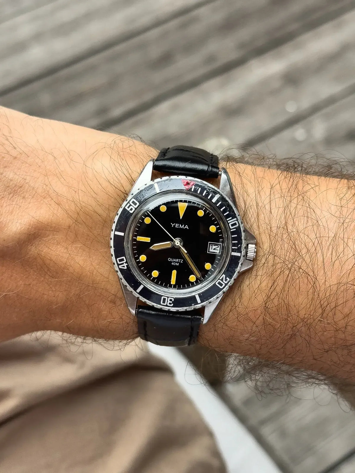 Yema vintage dive watch with black dial, yellow markers, and black leather strap on wrist