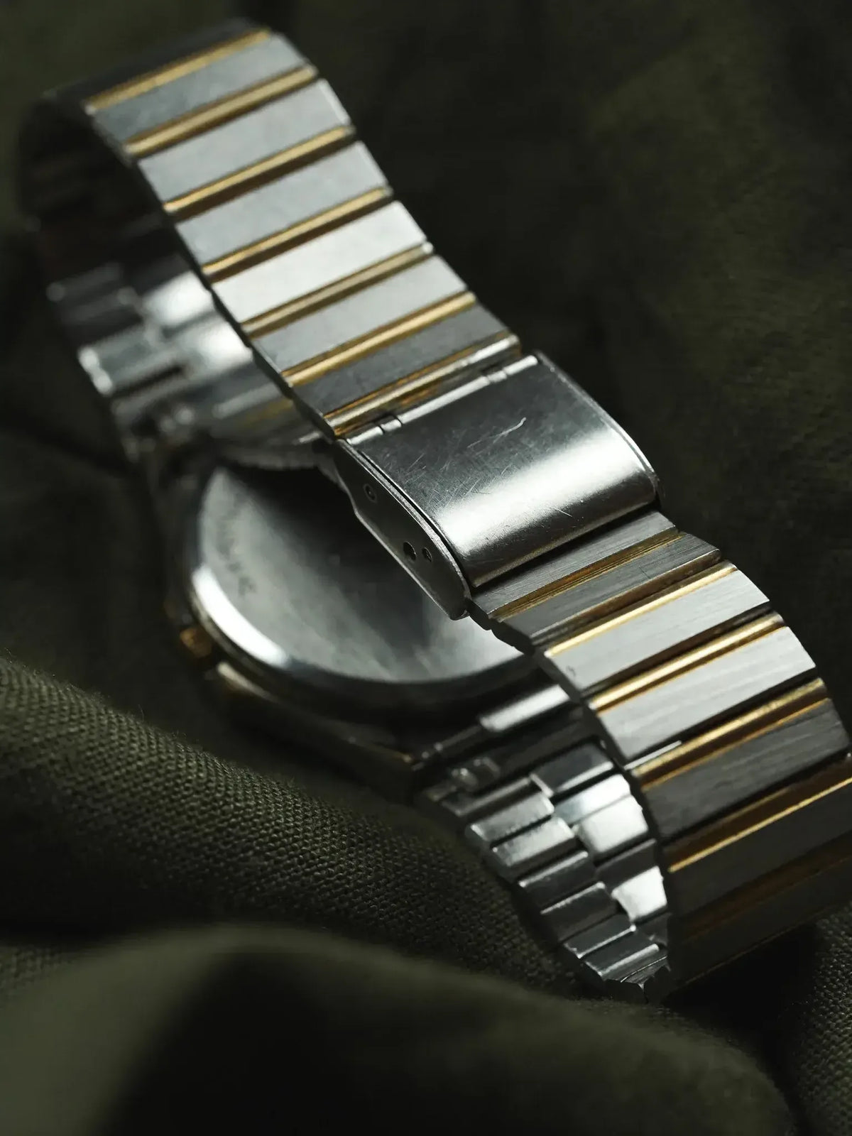 Vintage Omega watch with two-tone steel and gold bracelet, case back visible on dark fabric