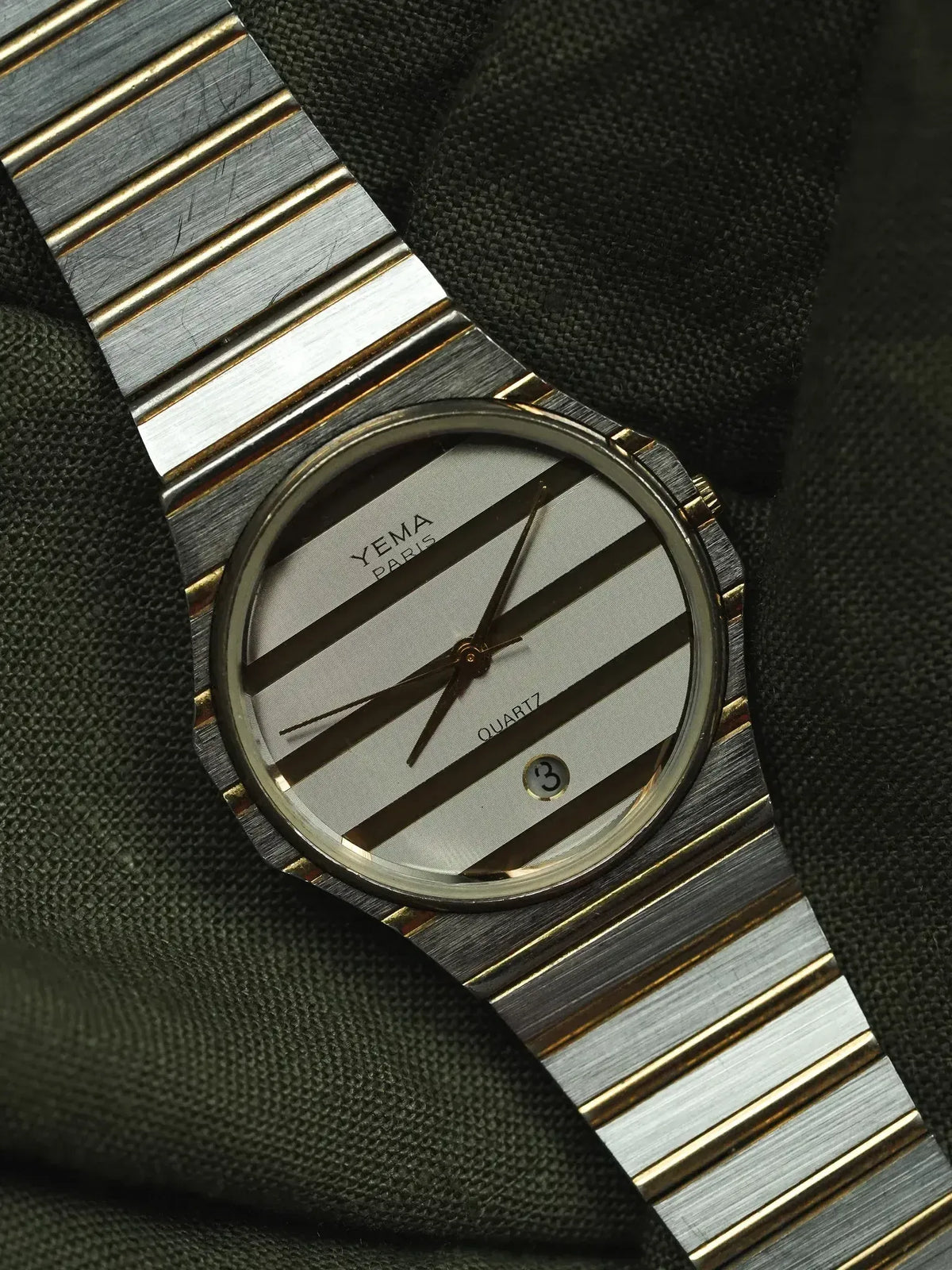 Omega vintage watch with striped dial, two-tone bracelet on dark fabric