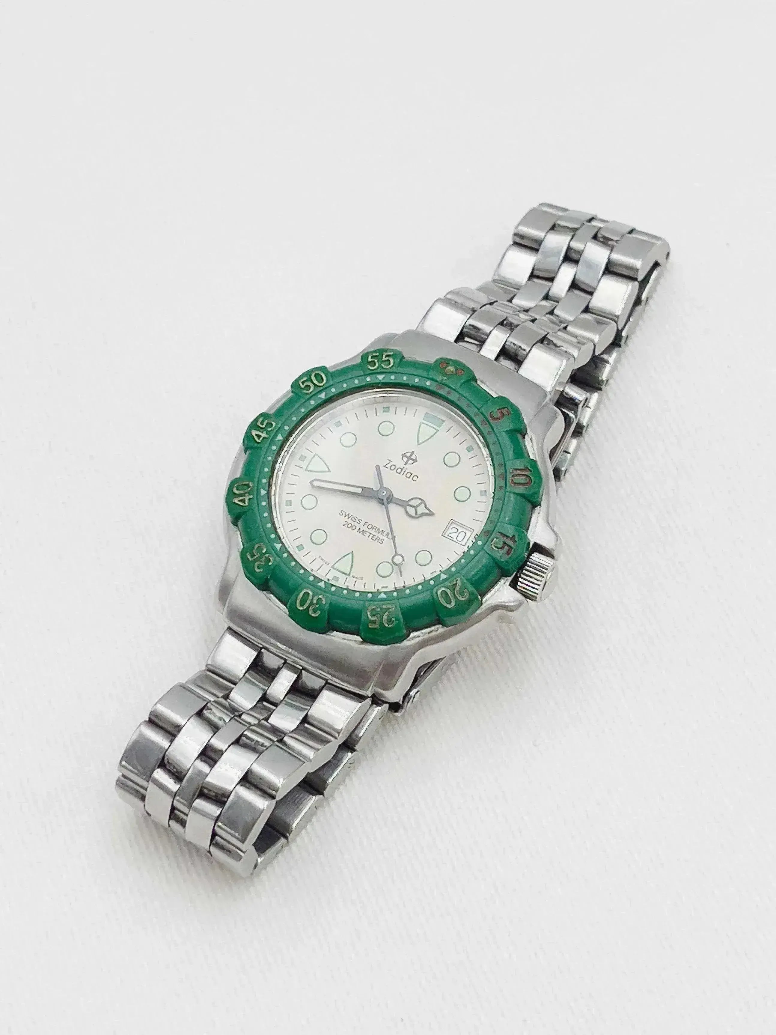 Zodiac vintage watch with green bezel, white dial, and steel bracelet on white background