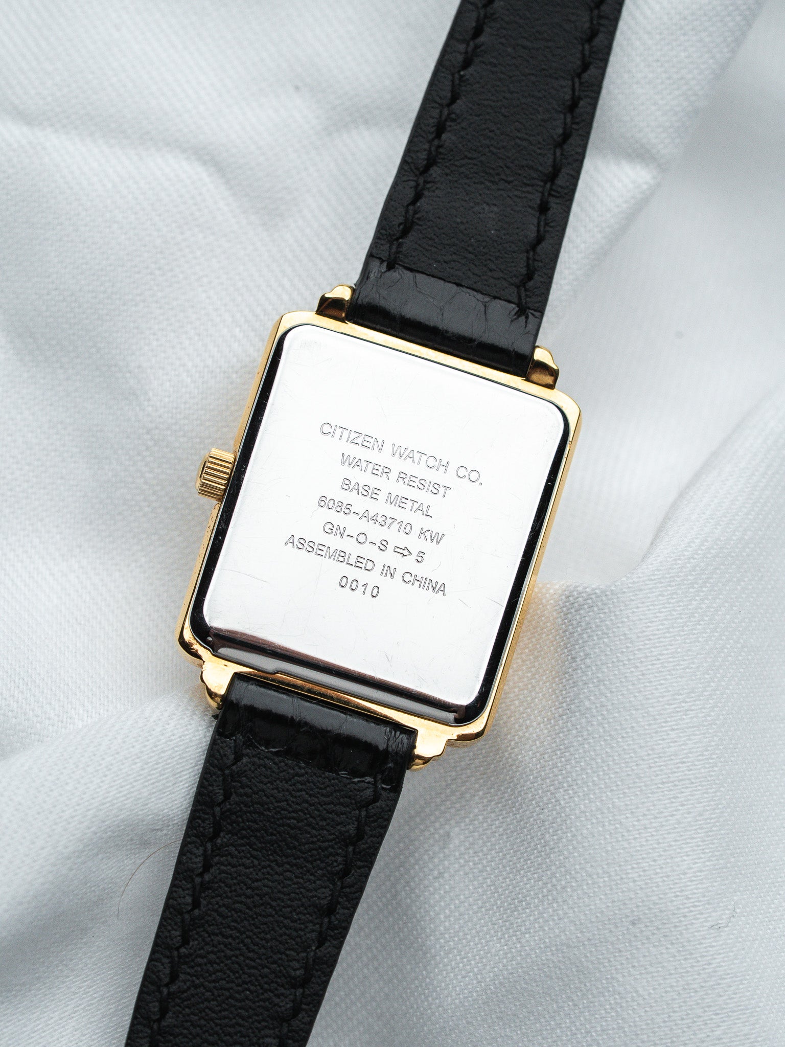Citizen watch with gold case, black leather strap, and engraved back details