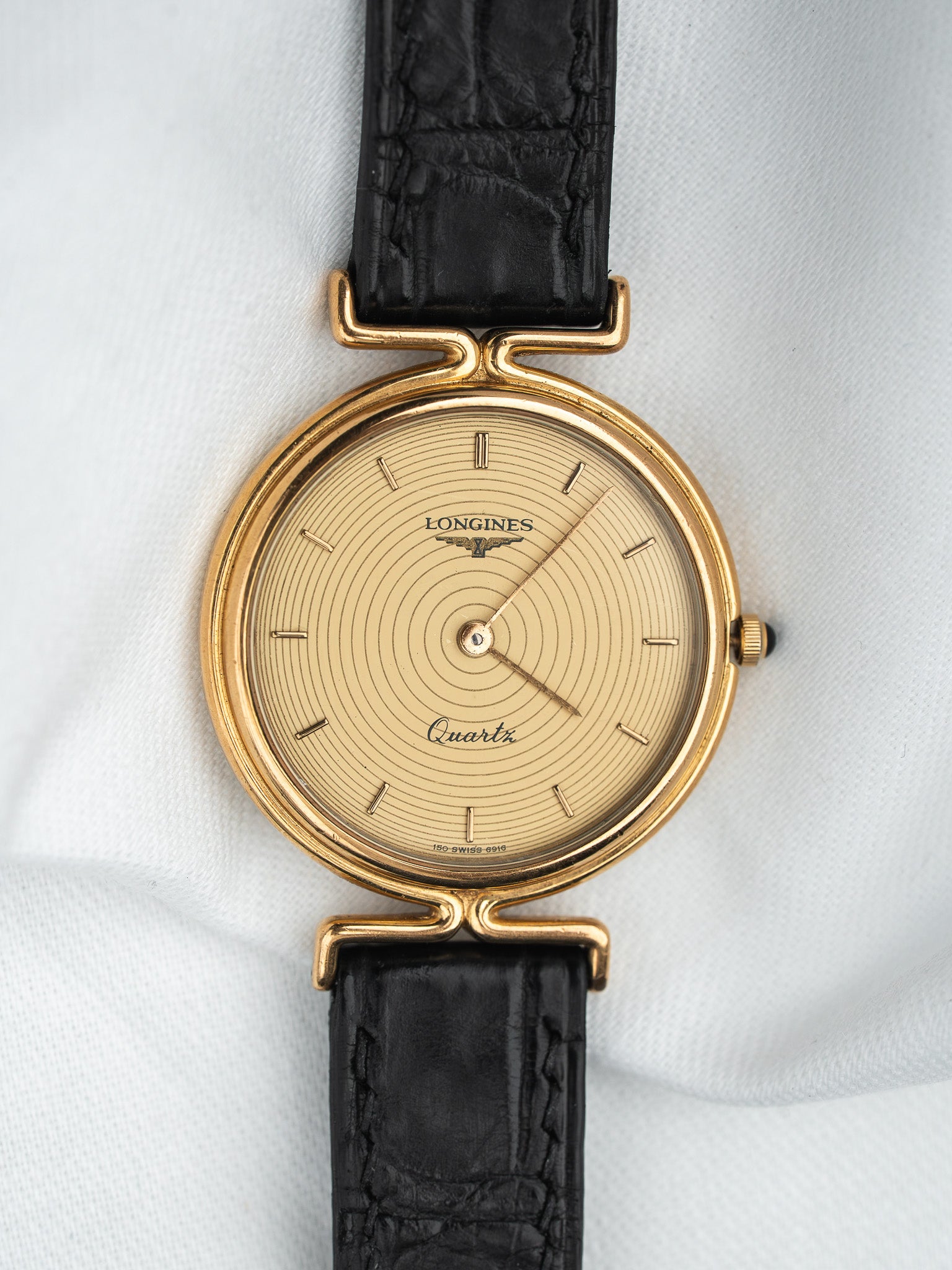 Longines vintage quartz watch with gold case, cream dial, and black leather strap