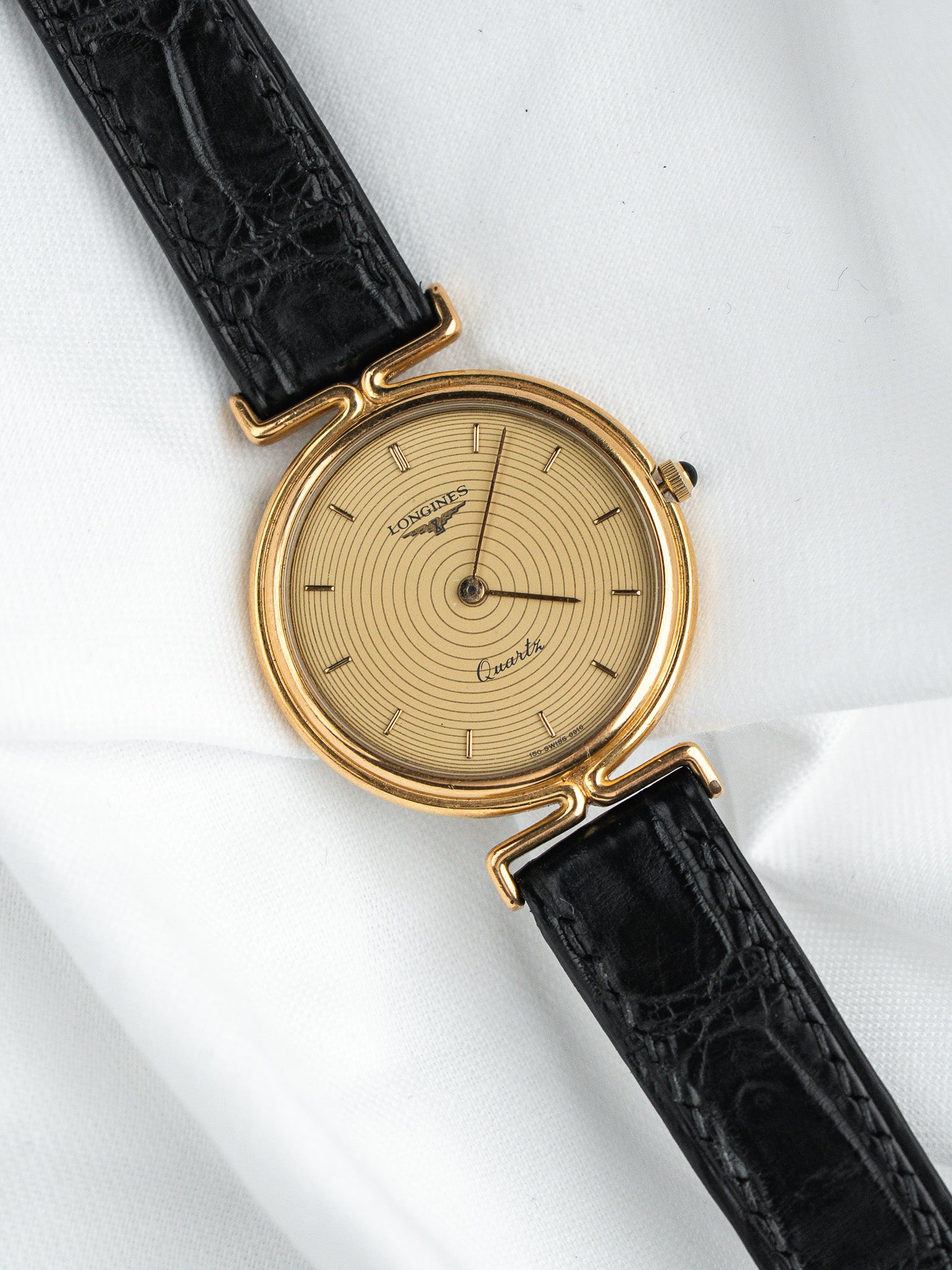 Longines vintage quartz watch with gold case, sunburst dial, and black alligator strap