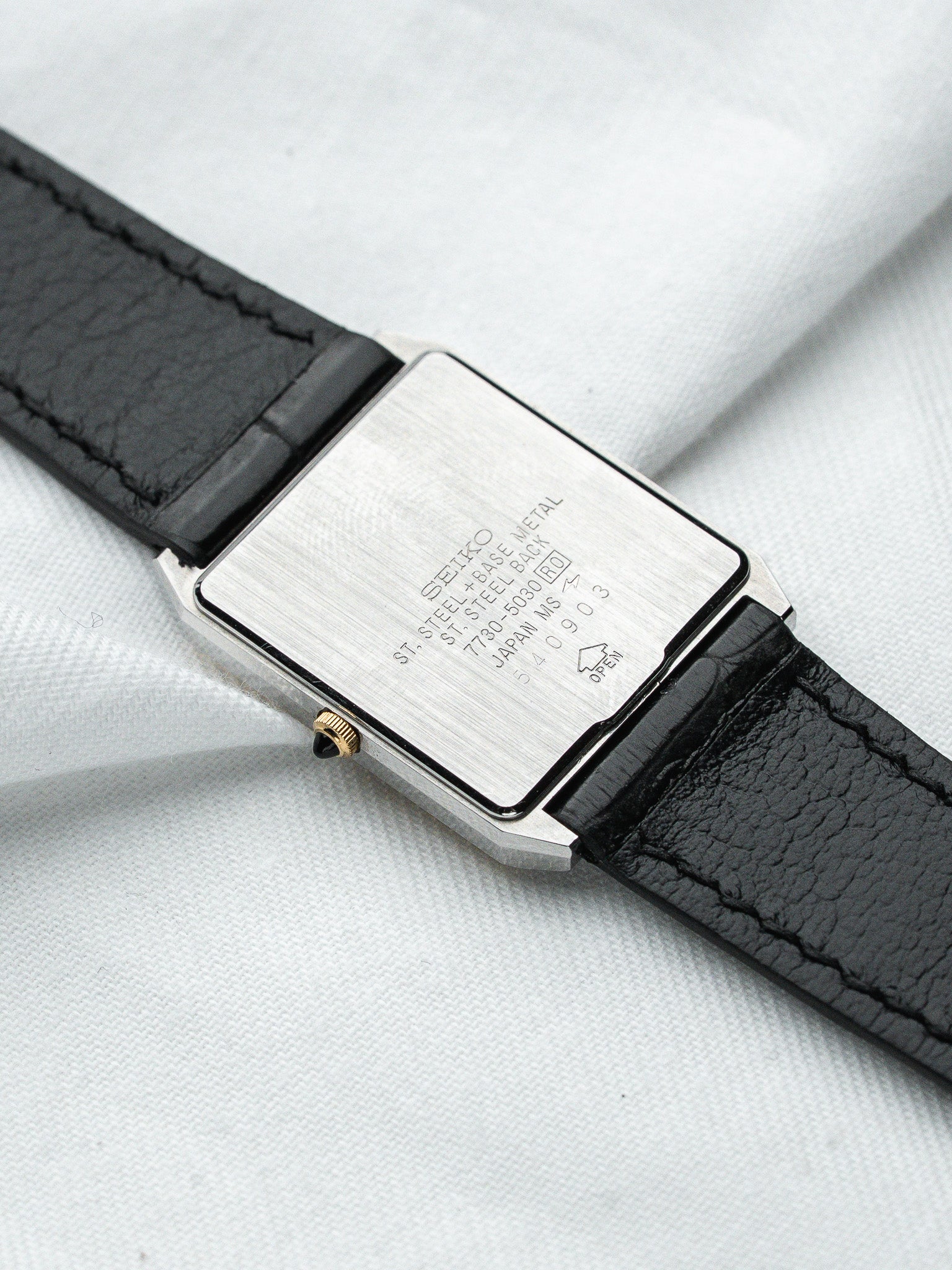 Seiko vintage watch with steel case, black leather strap, and engraved back details