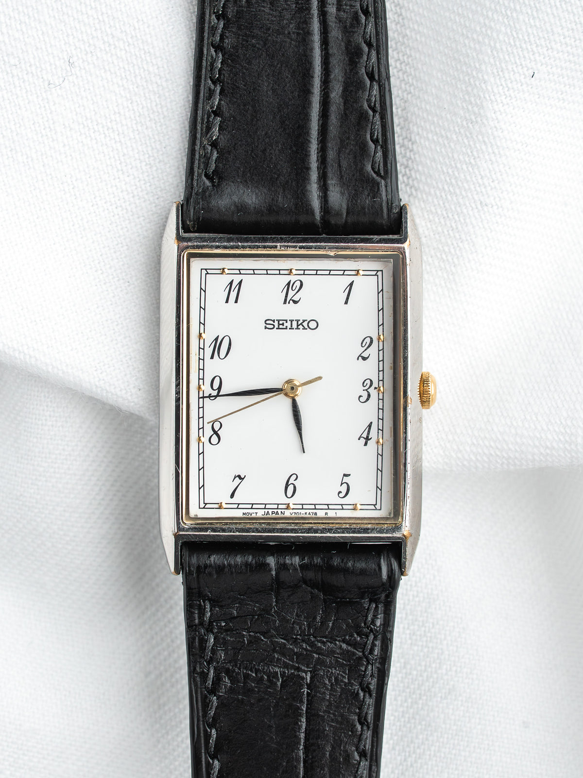 Seiko montre vintage avec cadran blanc, bracelet en cuir noir, boîtier rectangulaire