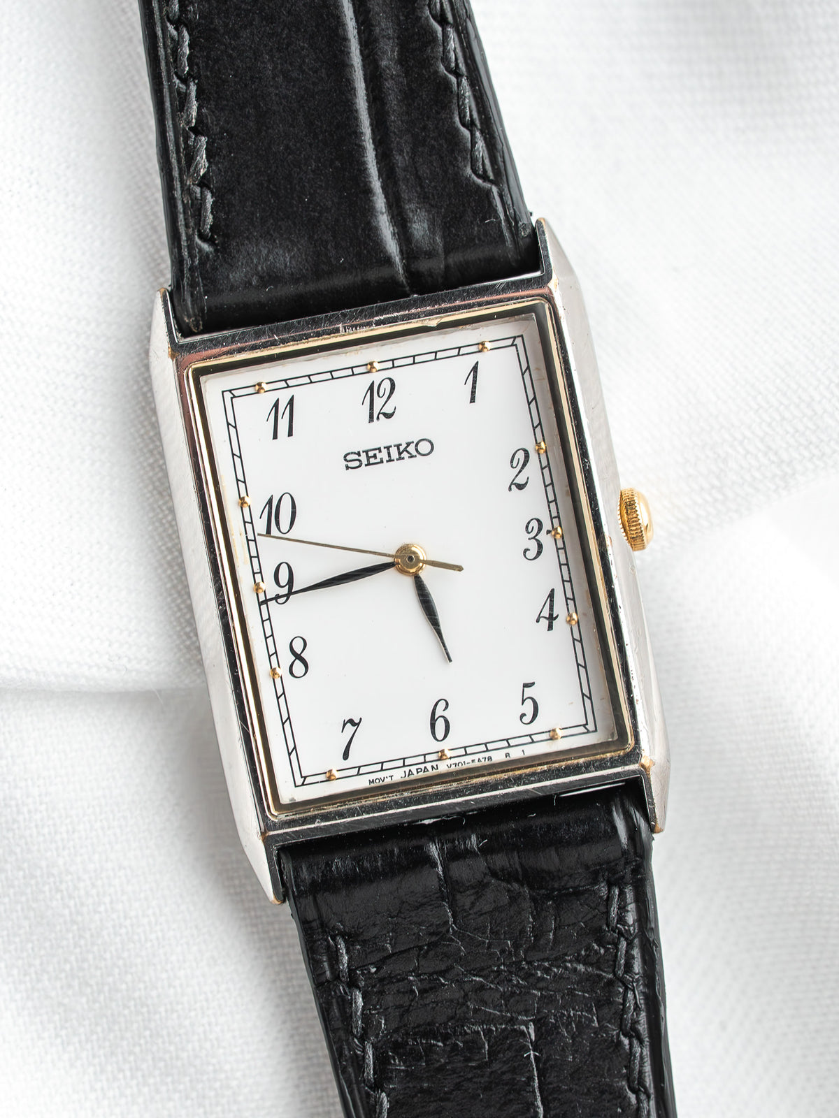 Seiko montre vintage avec cadran blanc, bracelet en cuir noir et accents dorés