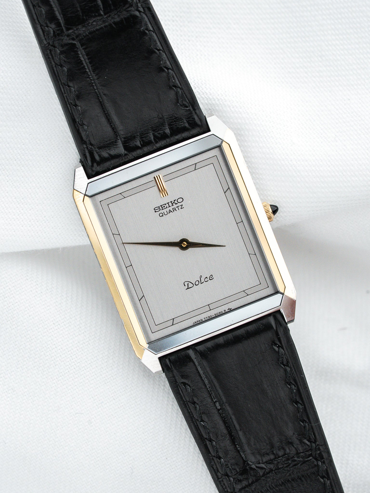 Seiko Dolce vintage quartz watch with silver dial, gold accents, black leather strap on white background