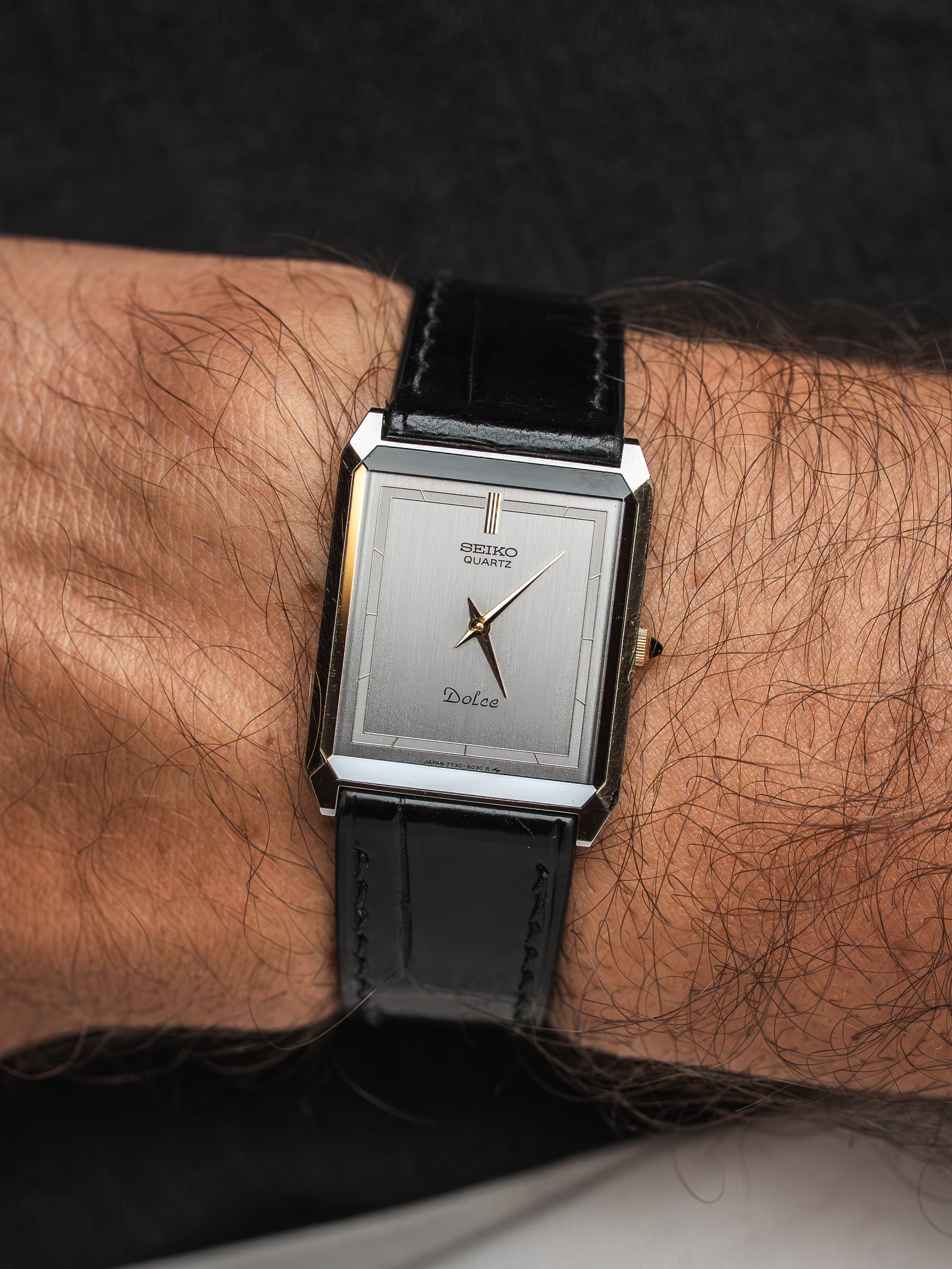 Seiko Dolce vintage quartz watch with silver dial, gold accents, black leather strap, worn on wrist