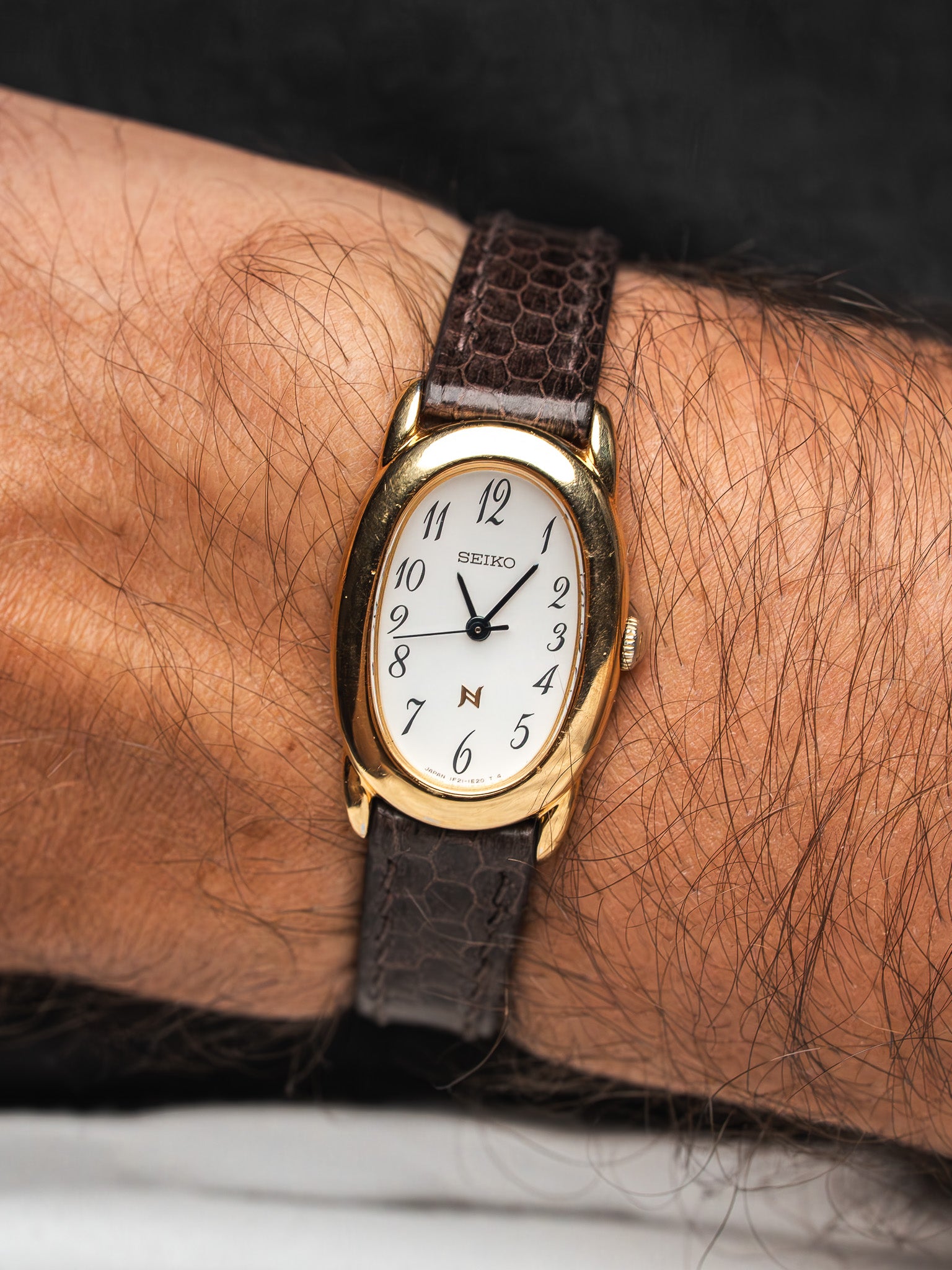 Seiko vintage watch with gold case, white dial, brown leather strap on wrist